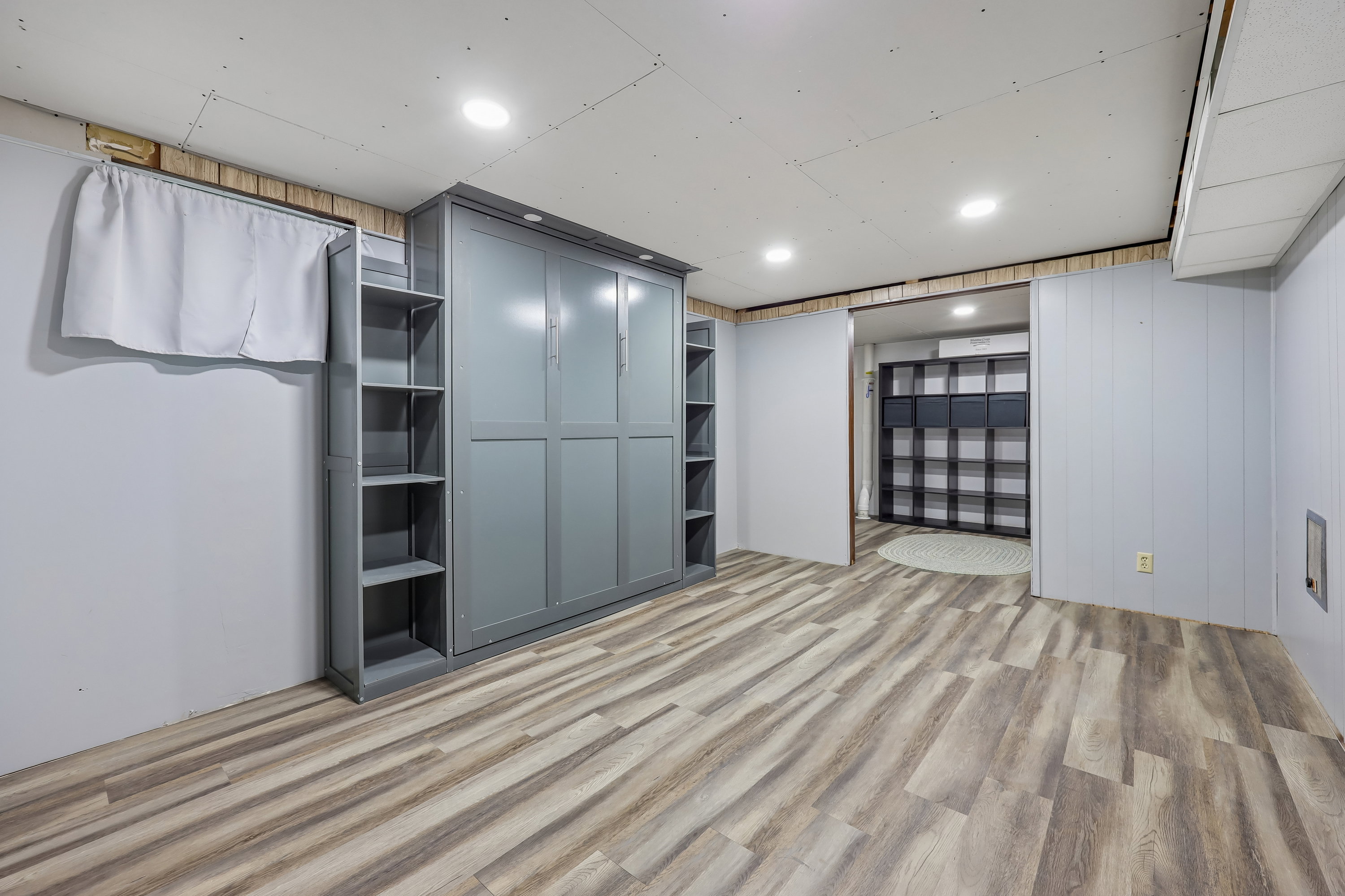 Spacious room featuring wood-finish flooring, recessed lighting, and a built-in wall unit with integrated shelving