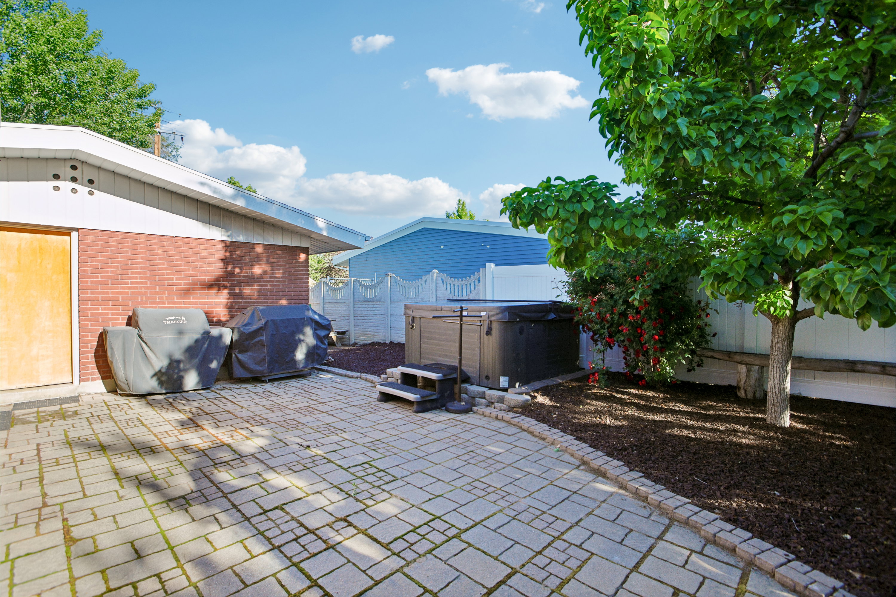 Exterior patio featuring paver stones, a hot tub with steps, and a decorative retaining wall