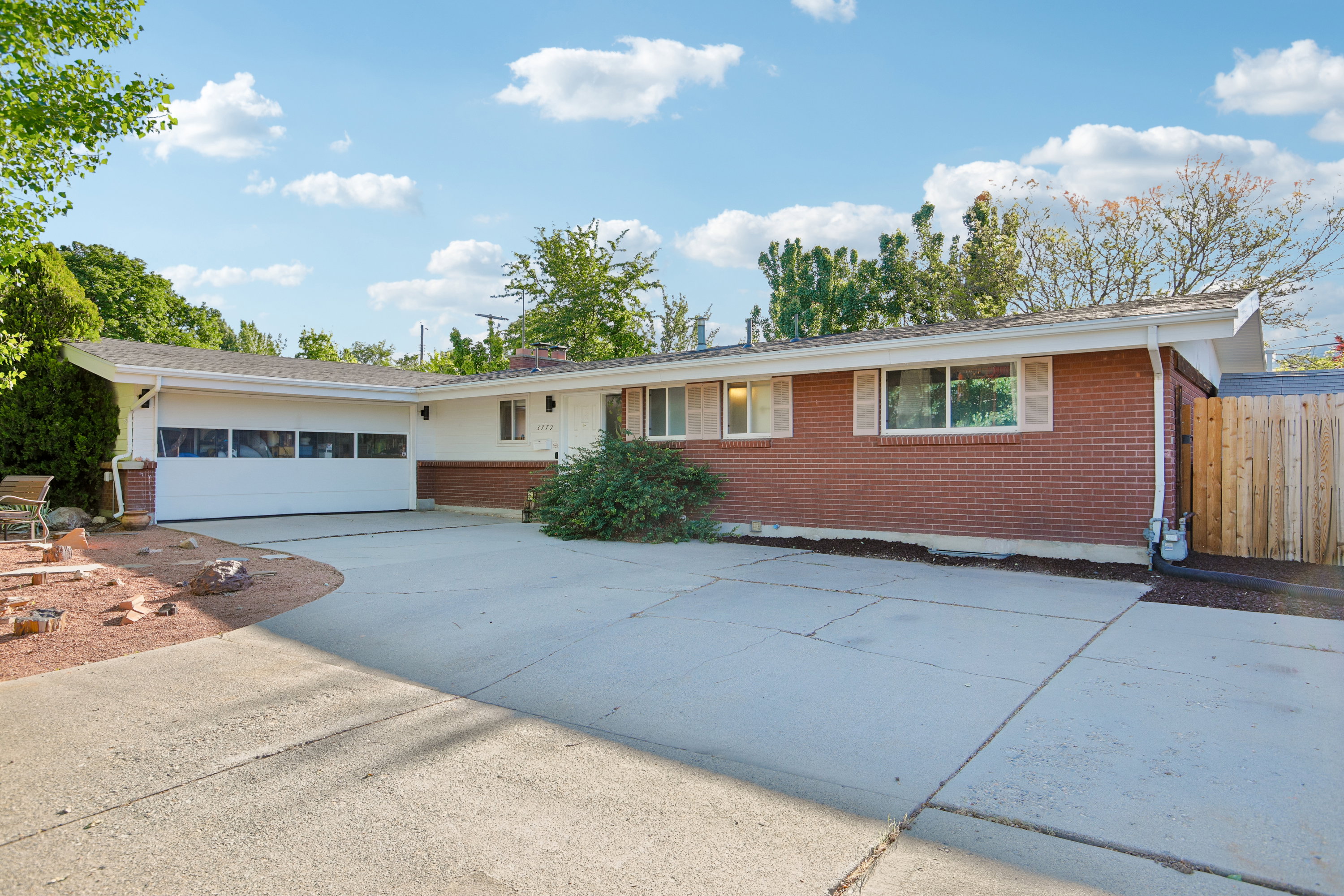 Ranch-style residence featuring a brick facade, attached two-car garage with paneling, and a concrete driveway
