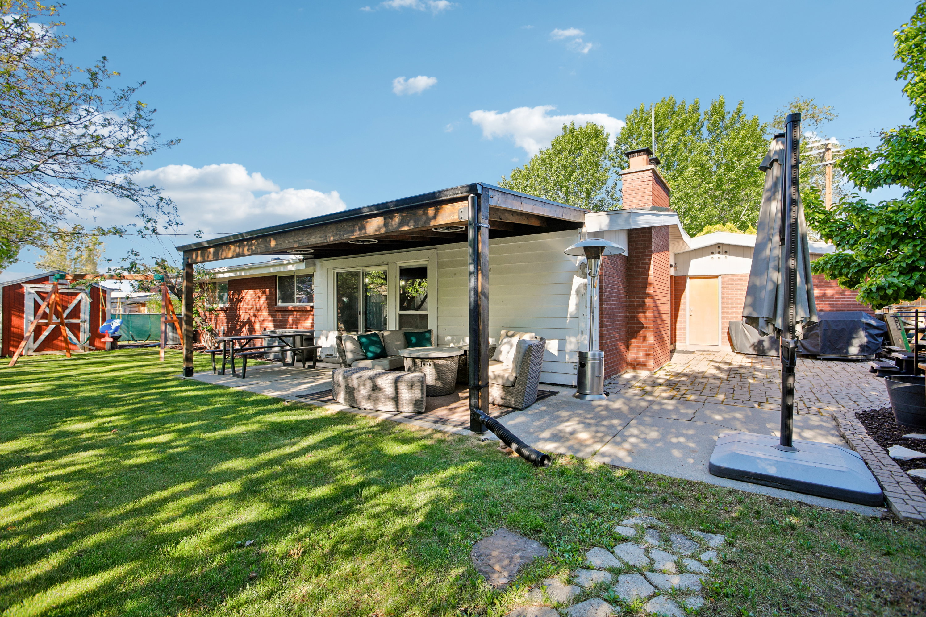 Expansive backyard featuring a lush lawn and a covered patio area
