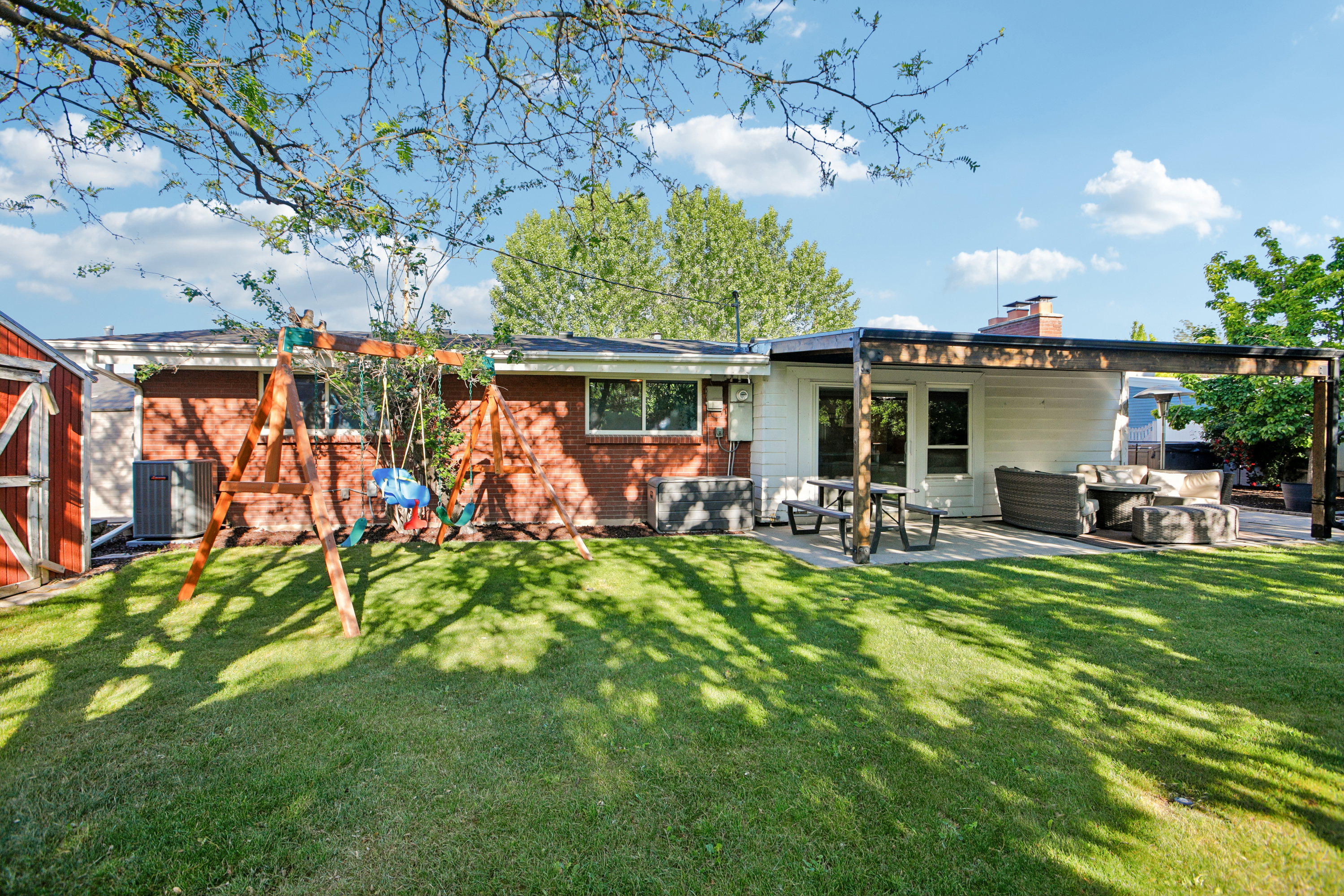 Expansive green lawn with mature trees providing partial shade