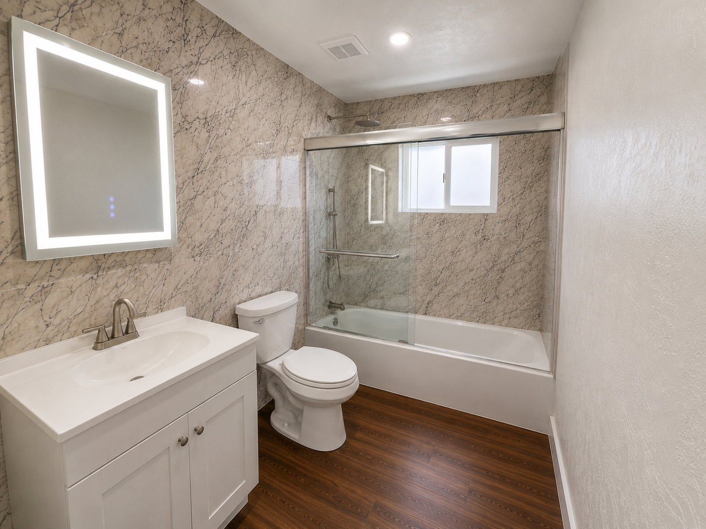 Modern bathroom featuring an illuminated mirror, white vanity with integrated sink, wood-finish flooring, a toilet, and a bathtub with a sliding glass enclosure