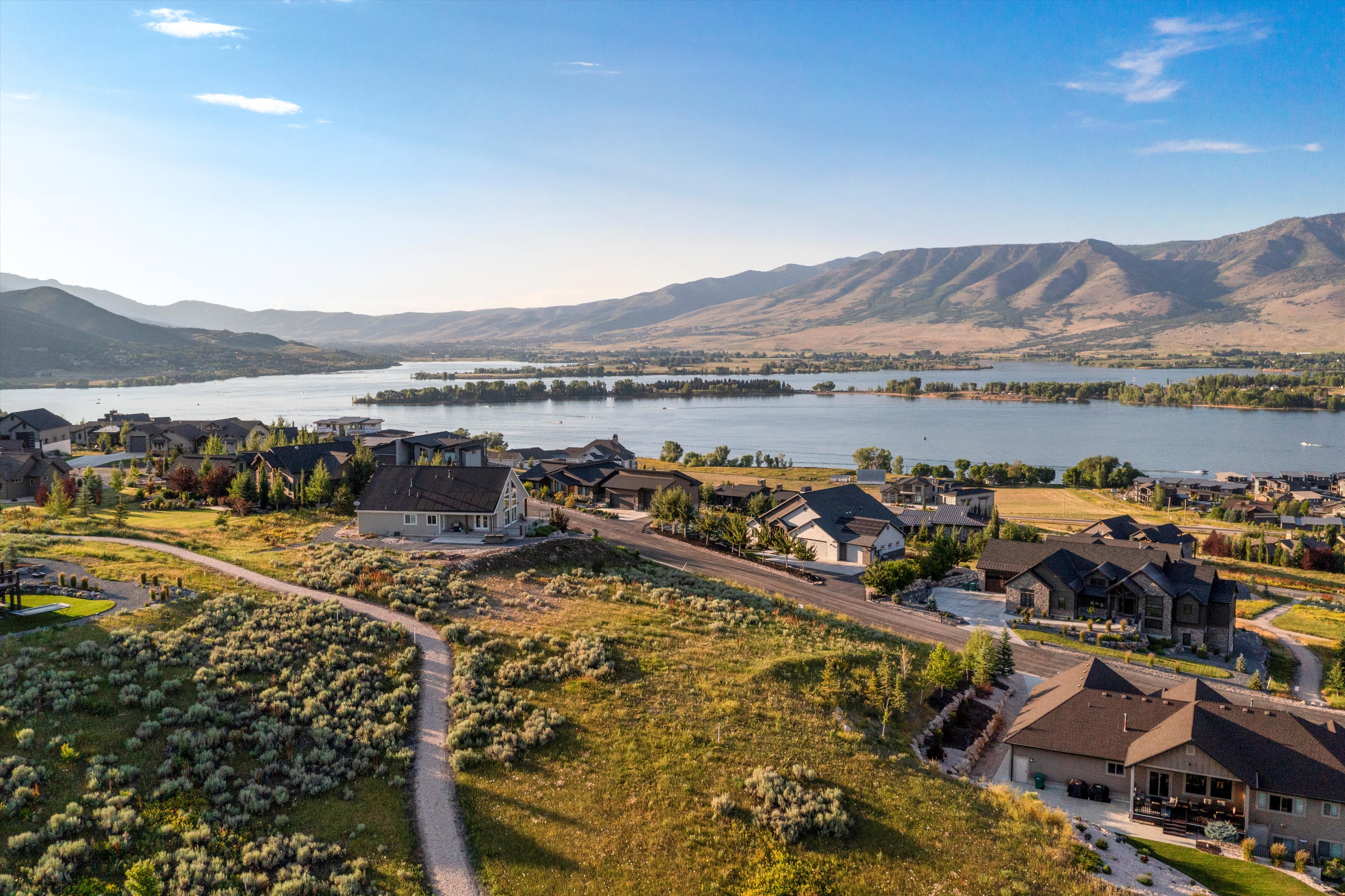 Expansive aerial perspective showcasing residential properties with a prominent lake and mountainous landscape