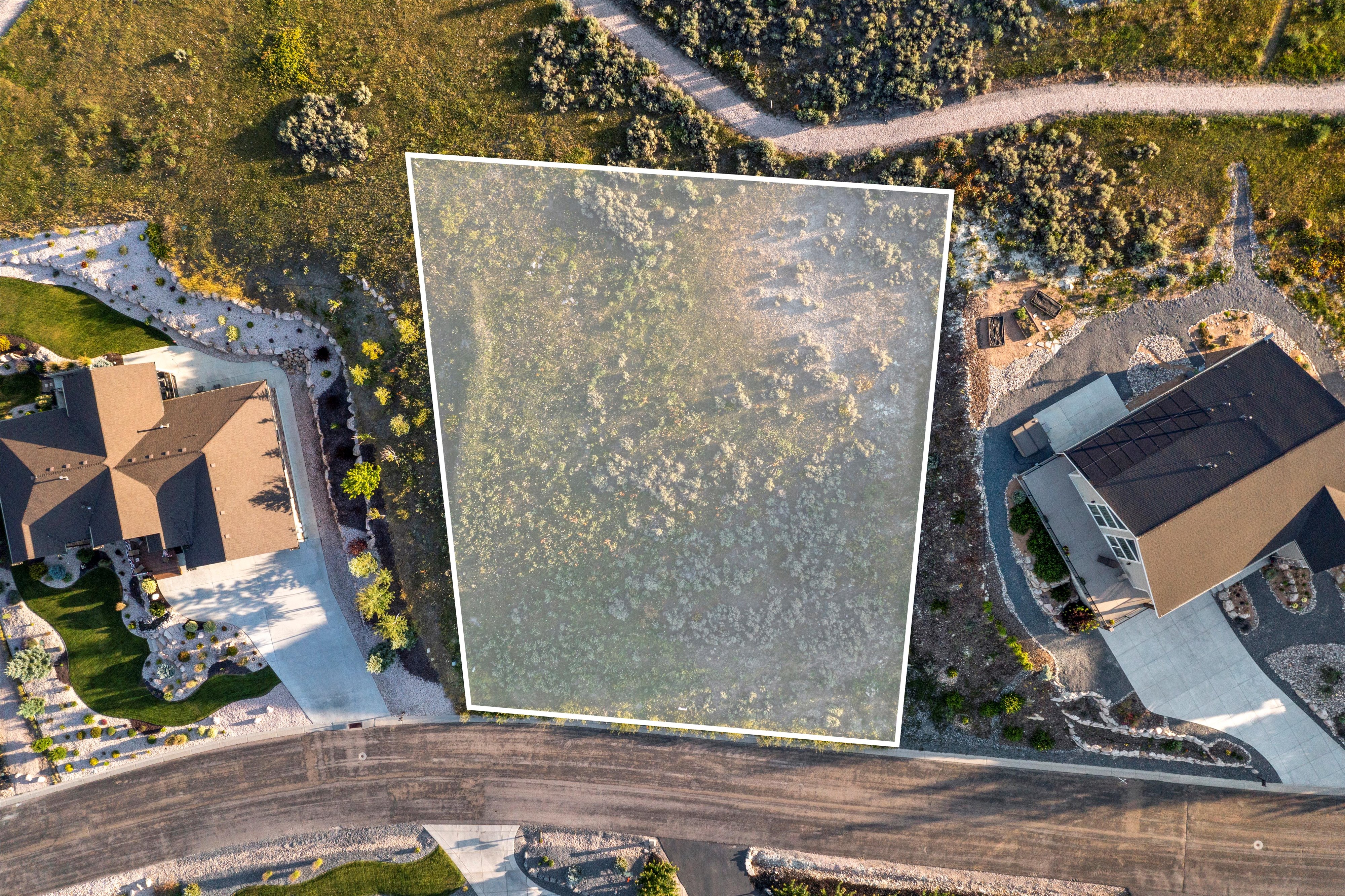 Expansive land parcel with surrounding residential properties, natural vegetation, and paved roads