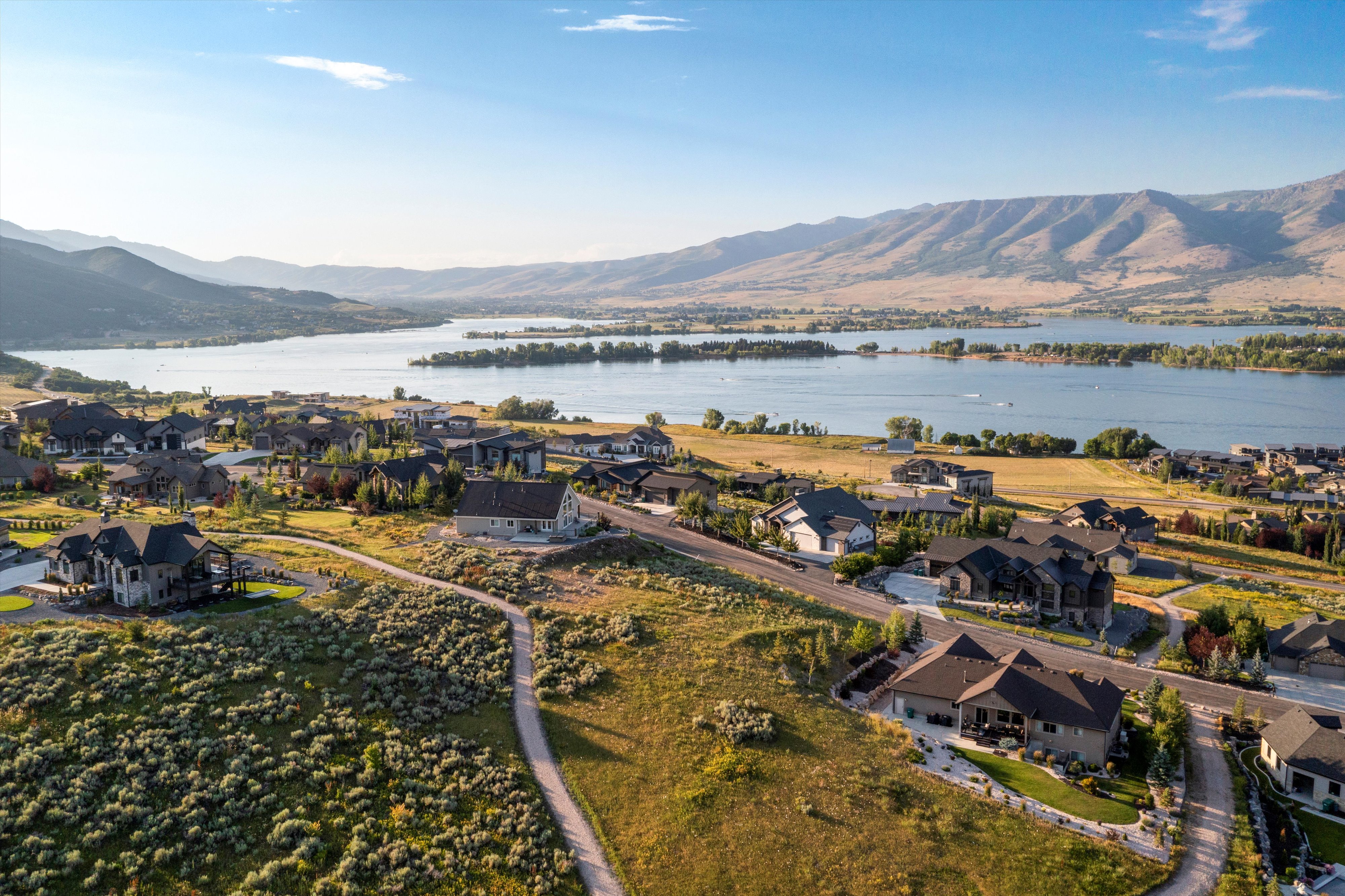Expansive aerial perspective showcasing a residential community with a large body of water and distant mountains