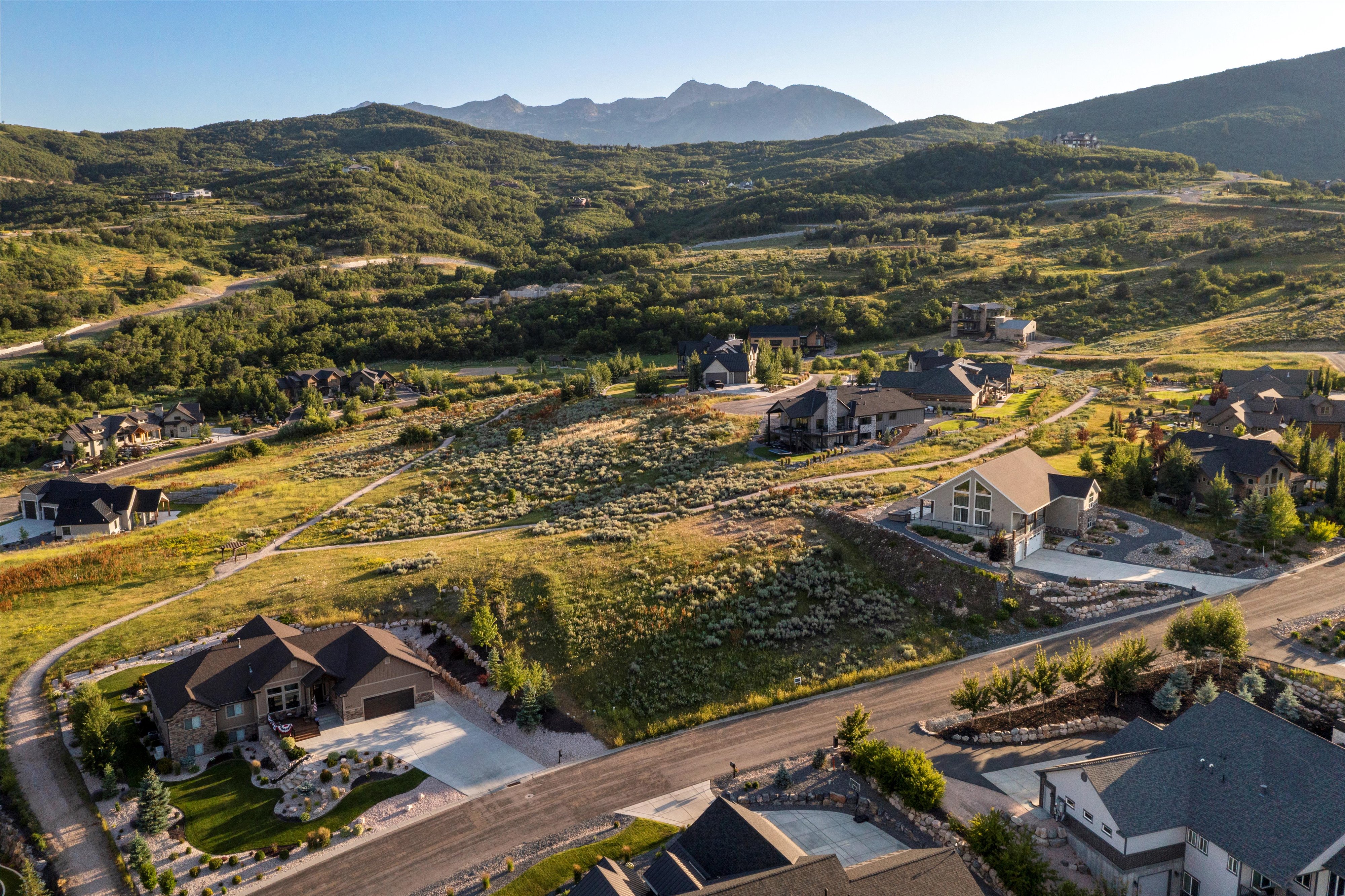 Expansive residential area featuring a mix of traditional and contemporary architecture, mature landscaping, and mountain backdrop