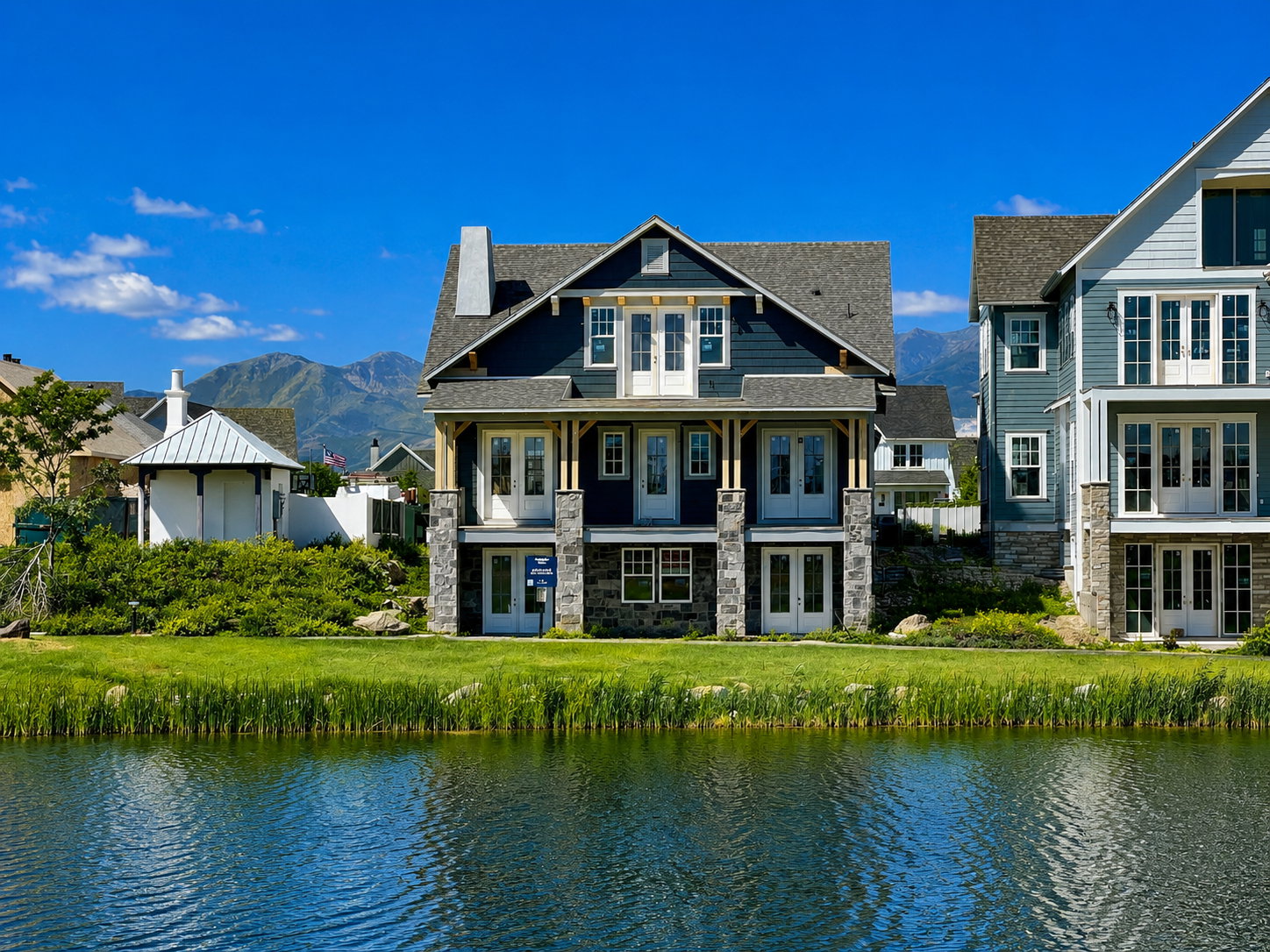Waterfront residence featuring a stone and siding exterior, multiple balconies, a covered porch, and a shingled roof