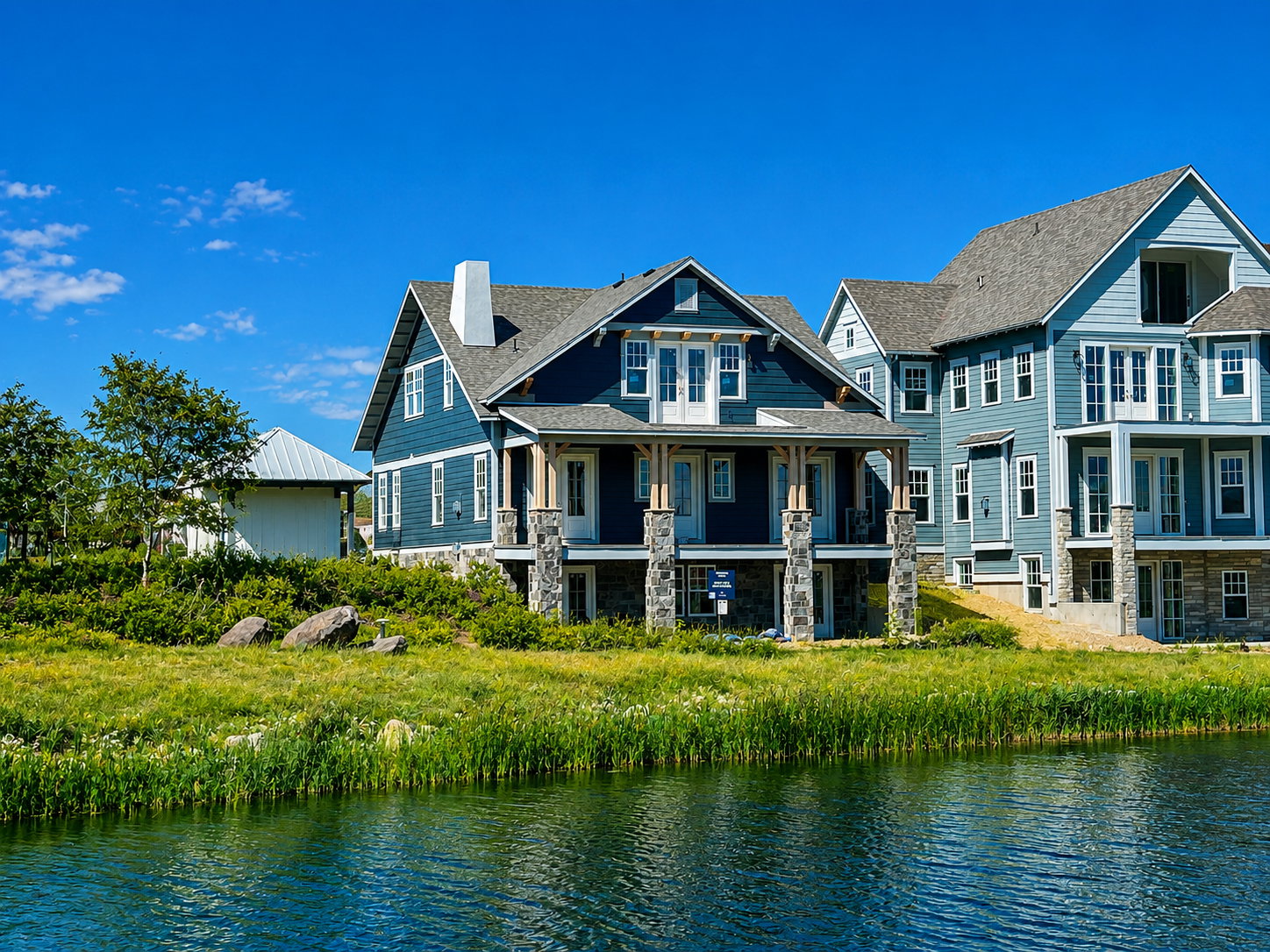 Waterfront property featuring multi-level blue siding and stone accents