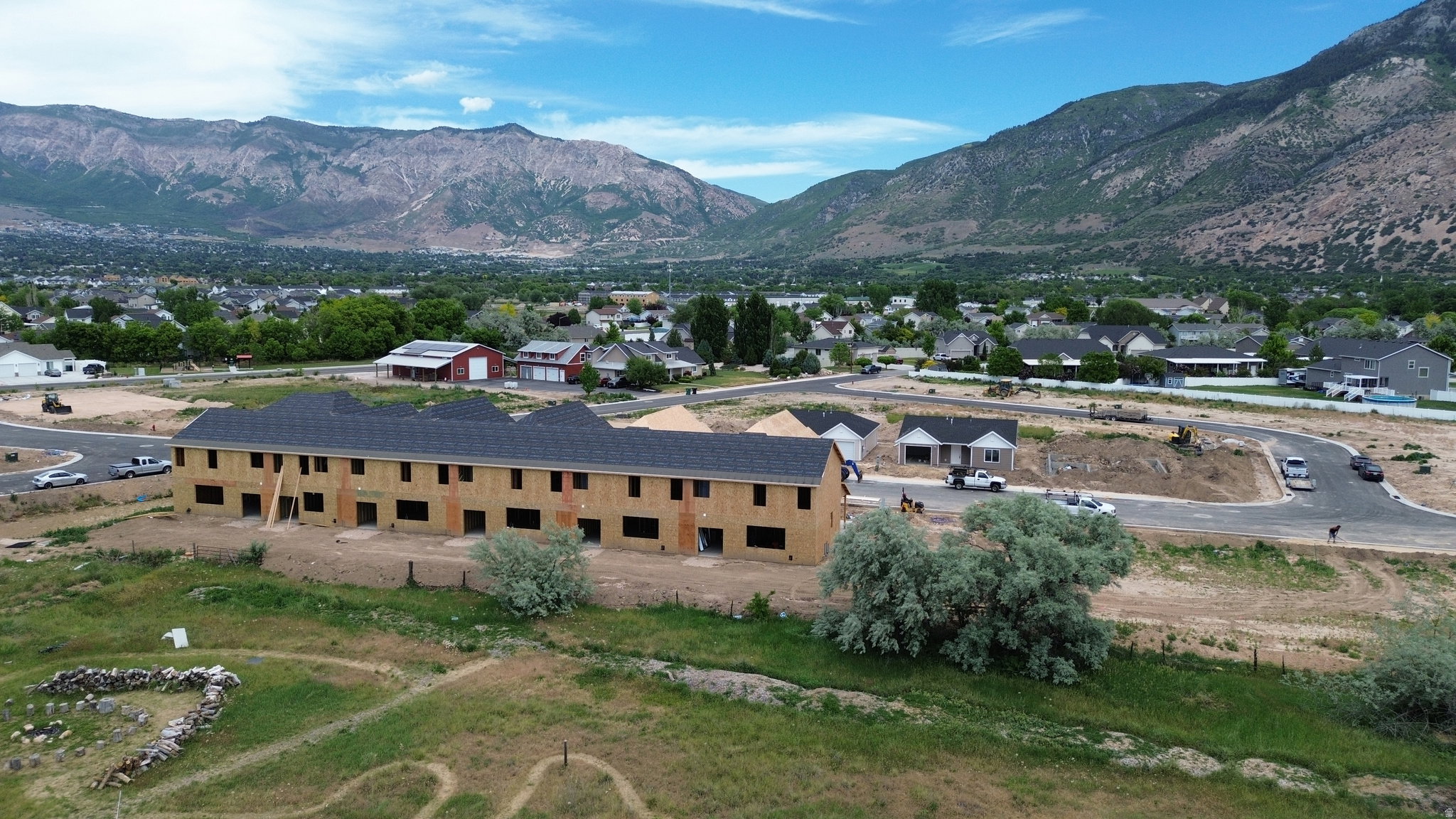 Multi-unit residential structure under construction featuring framed openings and a dark shingle roof