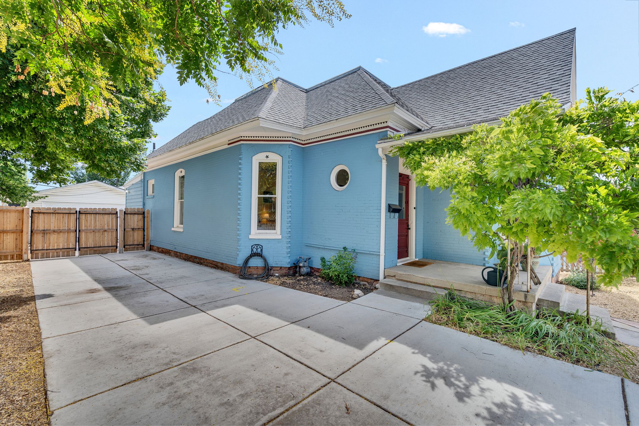 Blue exterior with white trim details, a covered front porch, and a dark red entry door