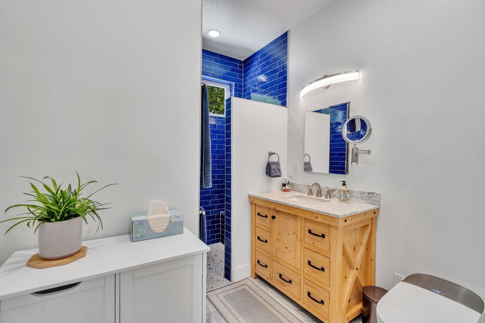 Bathroom featuring a wood vanity and  blue subway tile accents