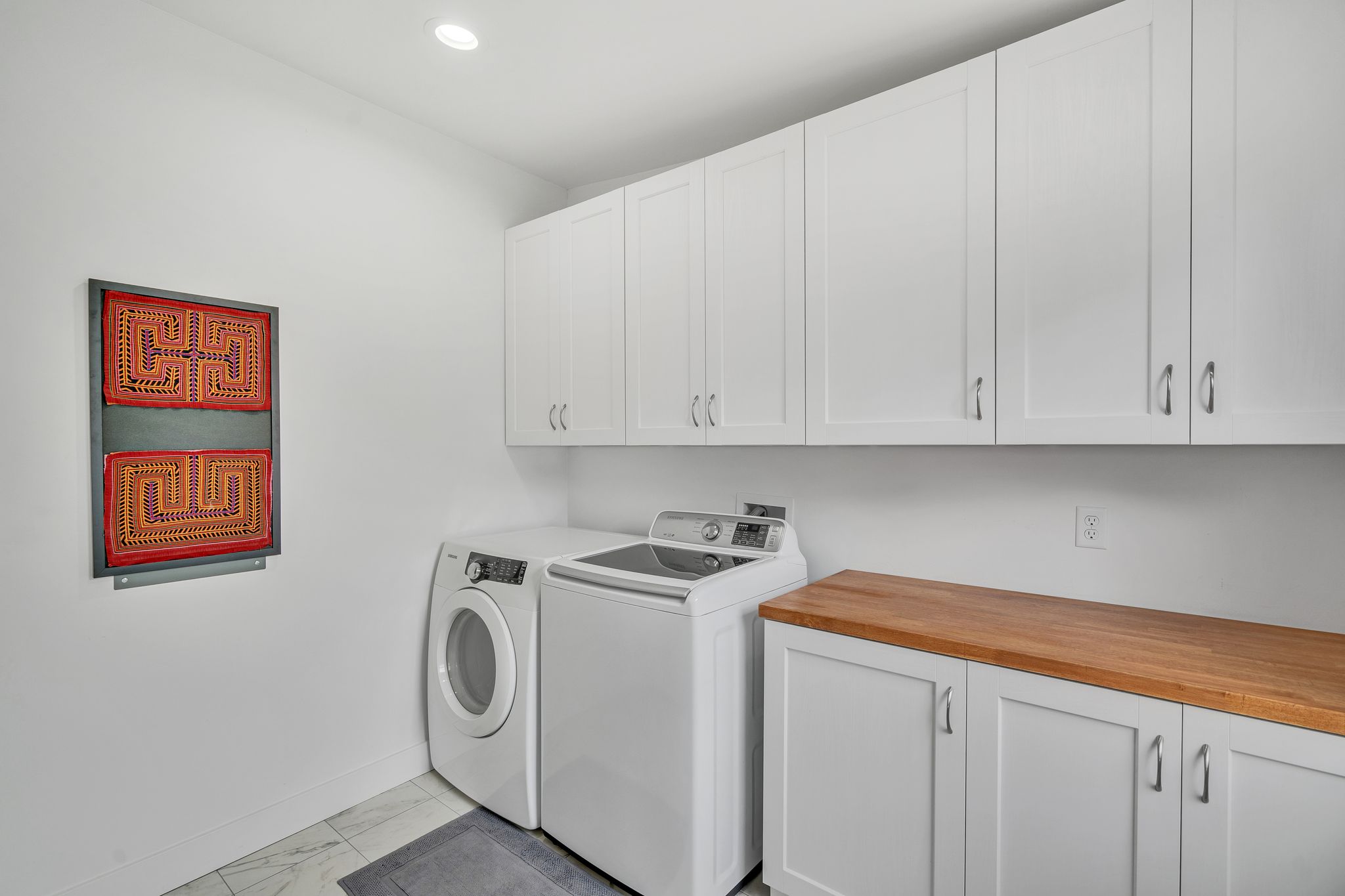 Laundry room featuring extensive white cabinetry, a wood-finish countertop, recessed lighting, and tile flooring