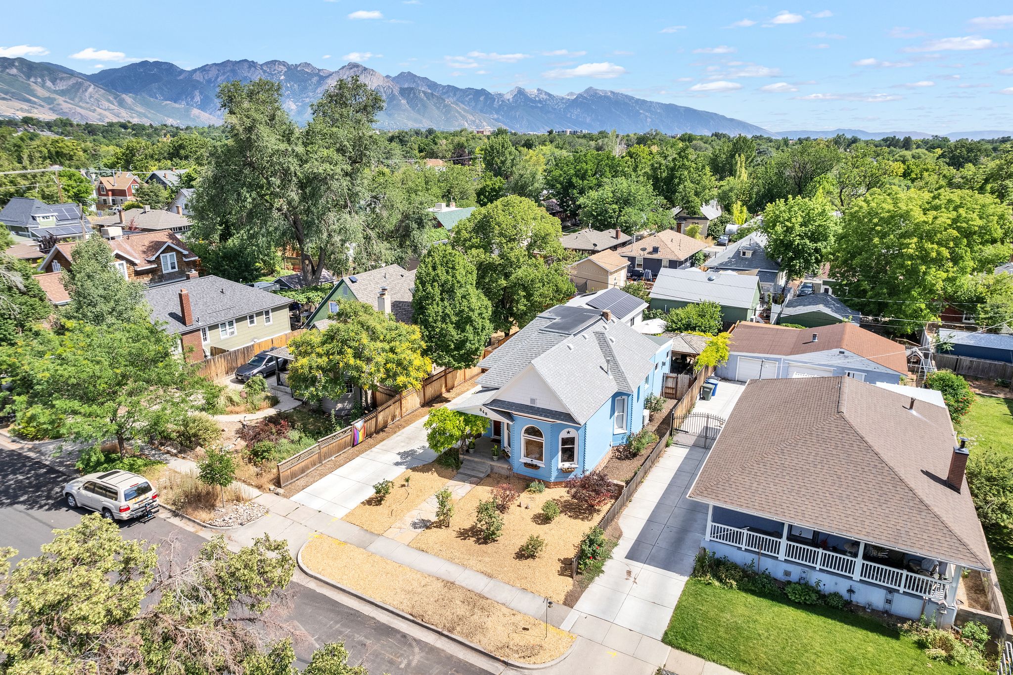 Blue residence with a light gray roof, solar panels, and a landscaped front yard
