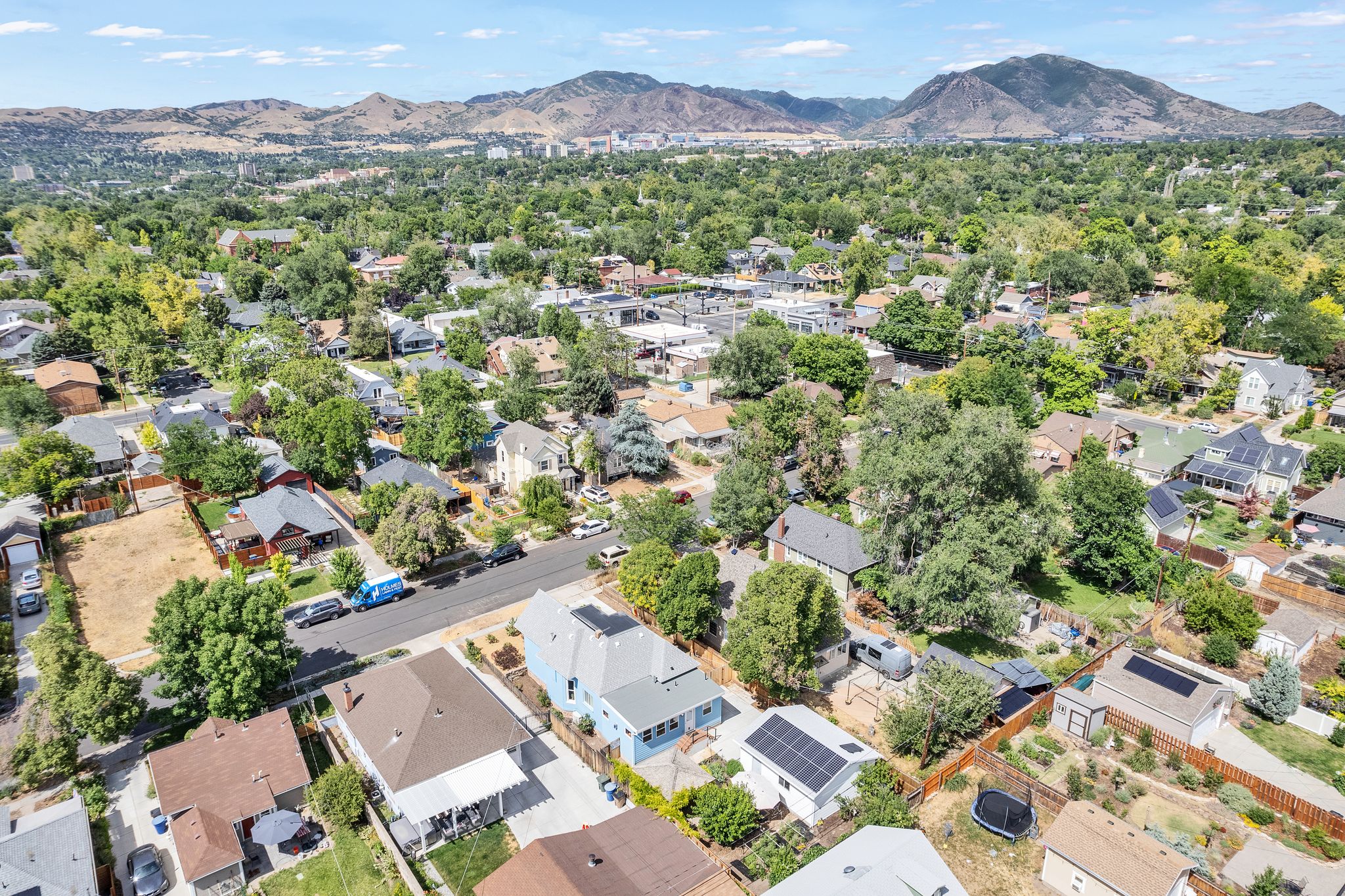 Aerial perspective showcasing a residential area with mature tree coverage and distant mountains
