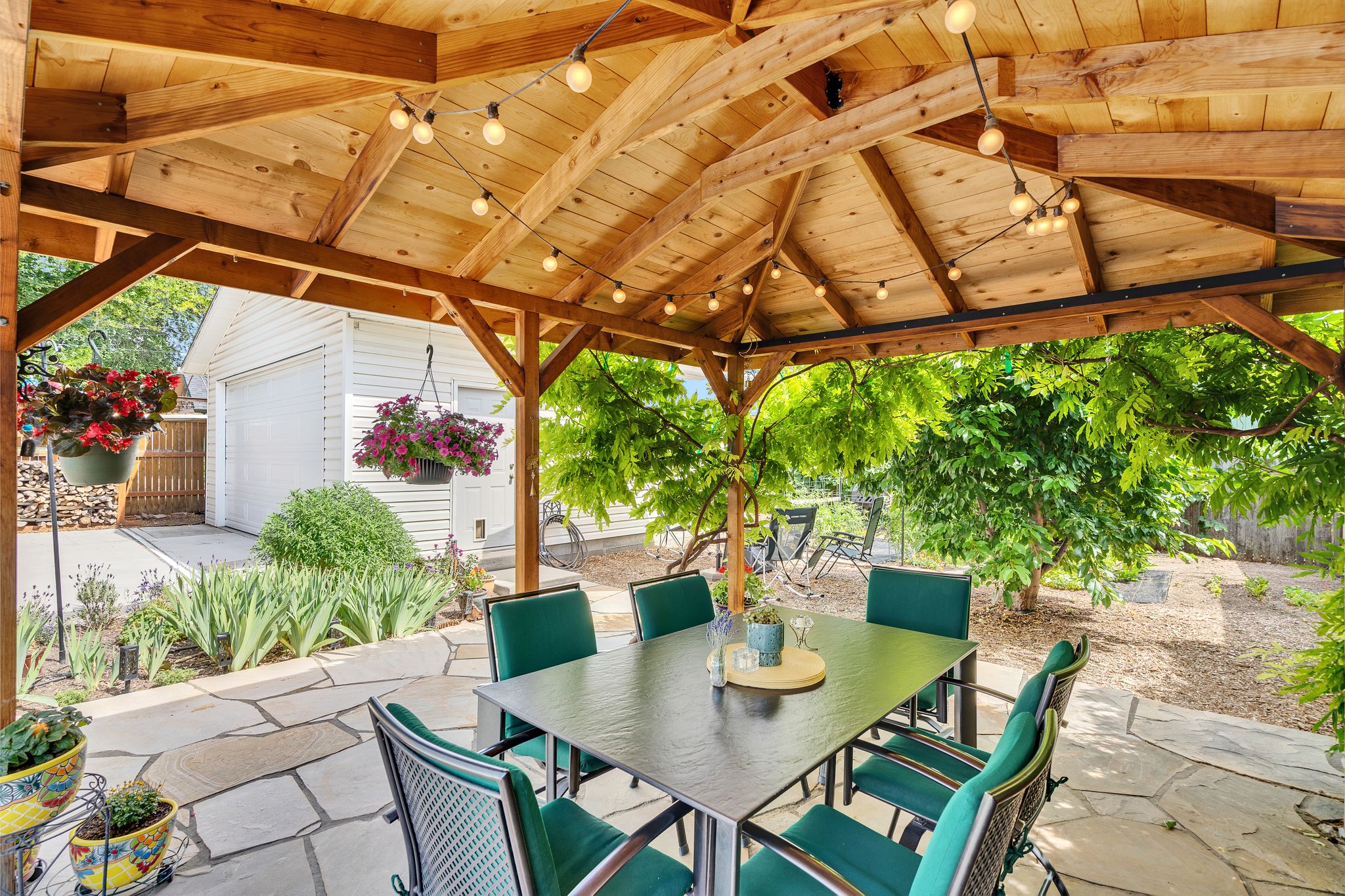 Expansive outdoor patio featuring a gazebo with built-in string lighting, flagstone patio and a landscaped garden