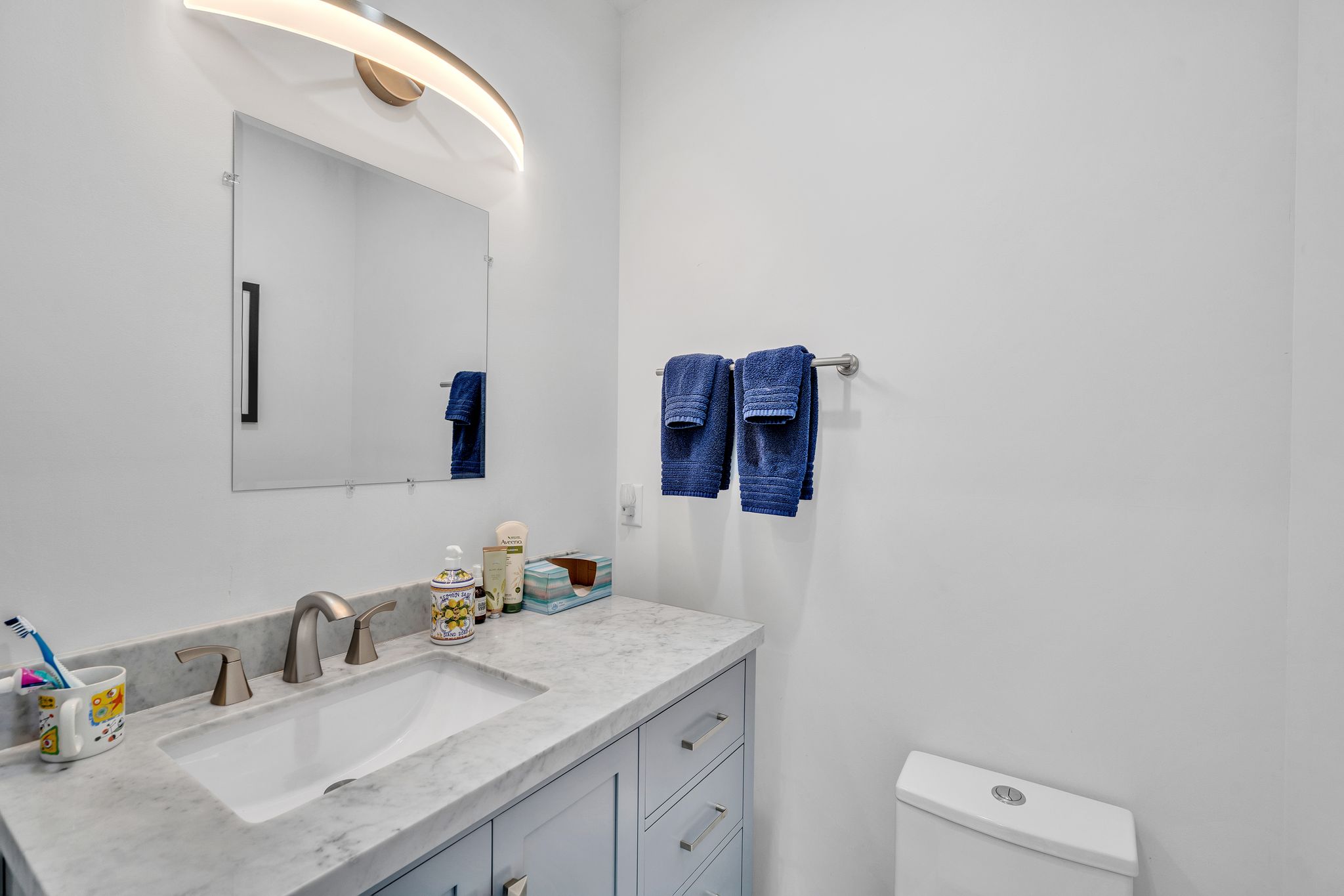 Bathroom vanity featuring a light gray shaker cabinet, white undermount sink, and brushed nickel faucet