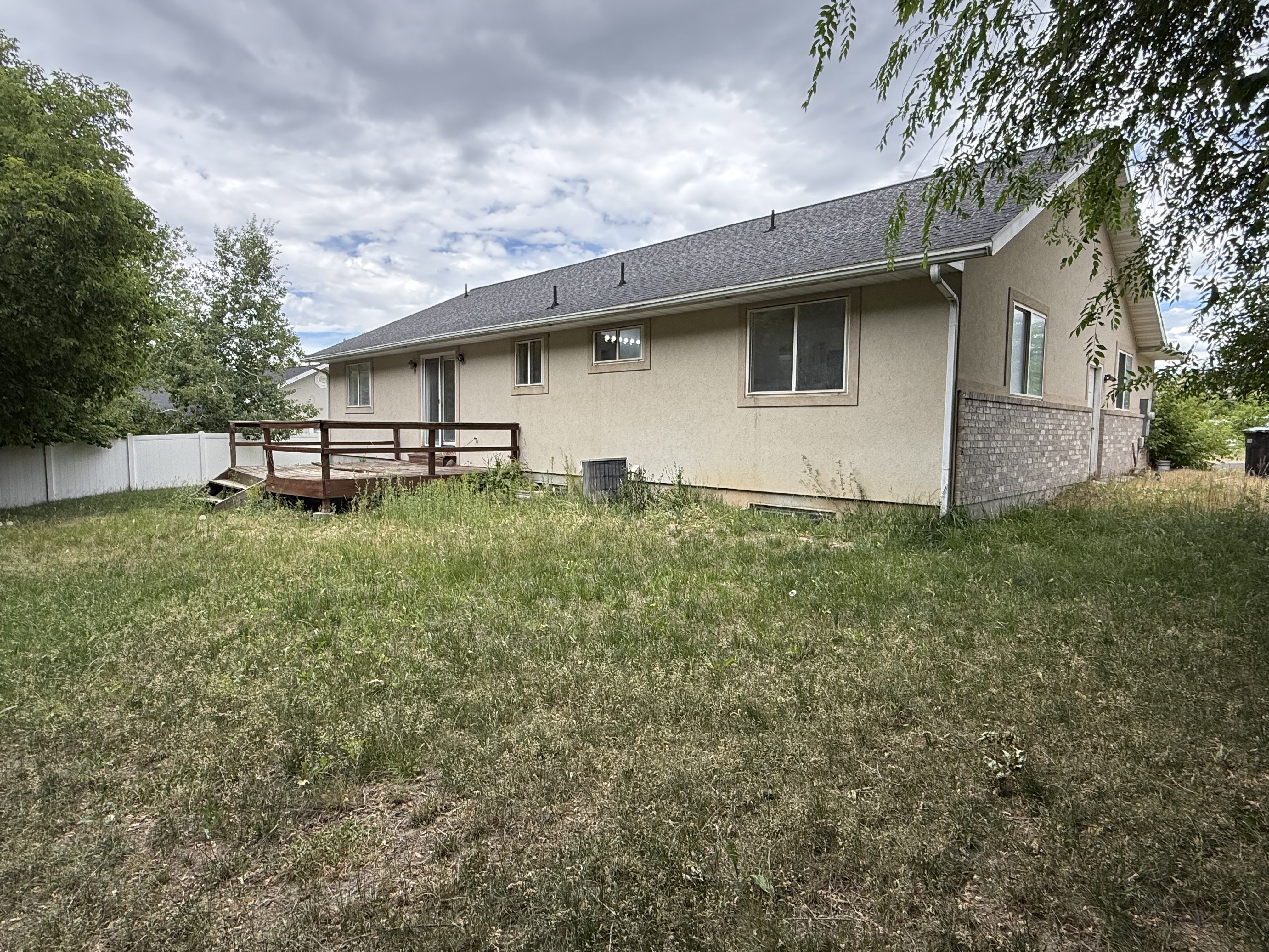 Rear exterior featuring a wood deck, sliding glass door, and multiple windows