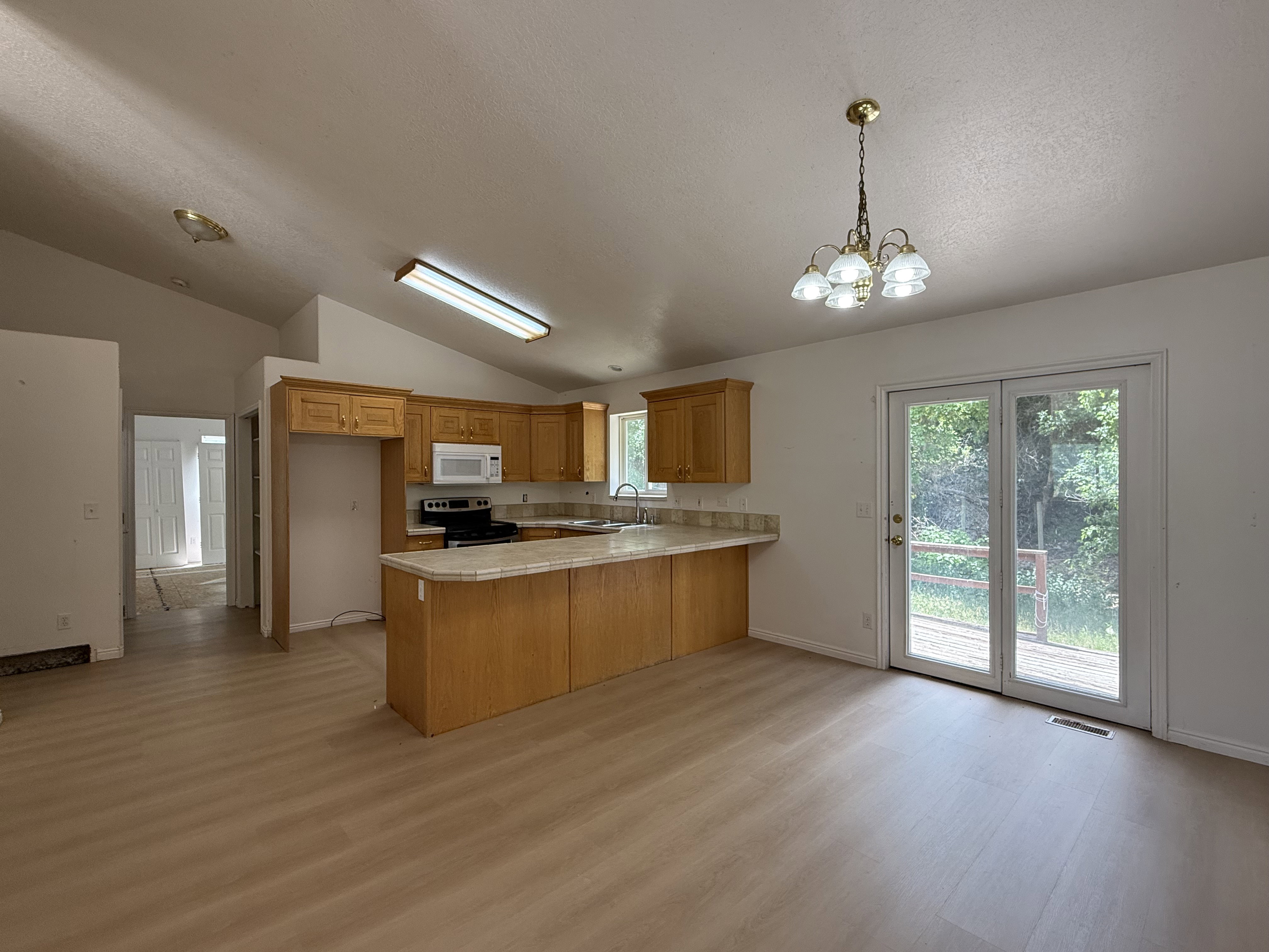 Eat-in kitchen featuring wood-finish cabinetry, light-toned countertops, and wood-finish flooring