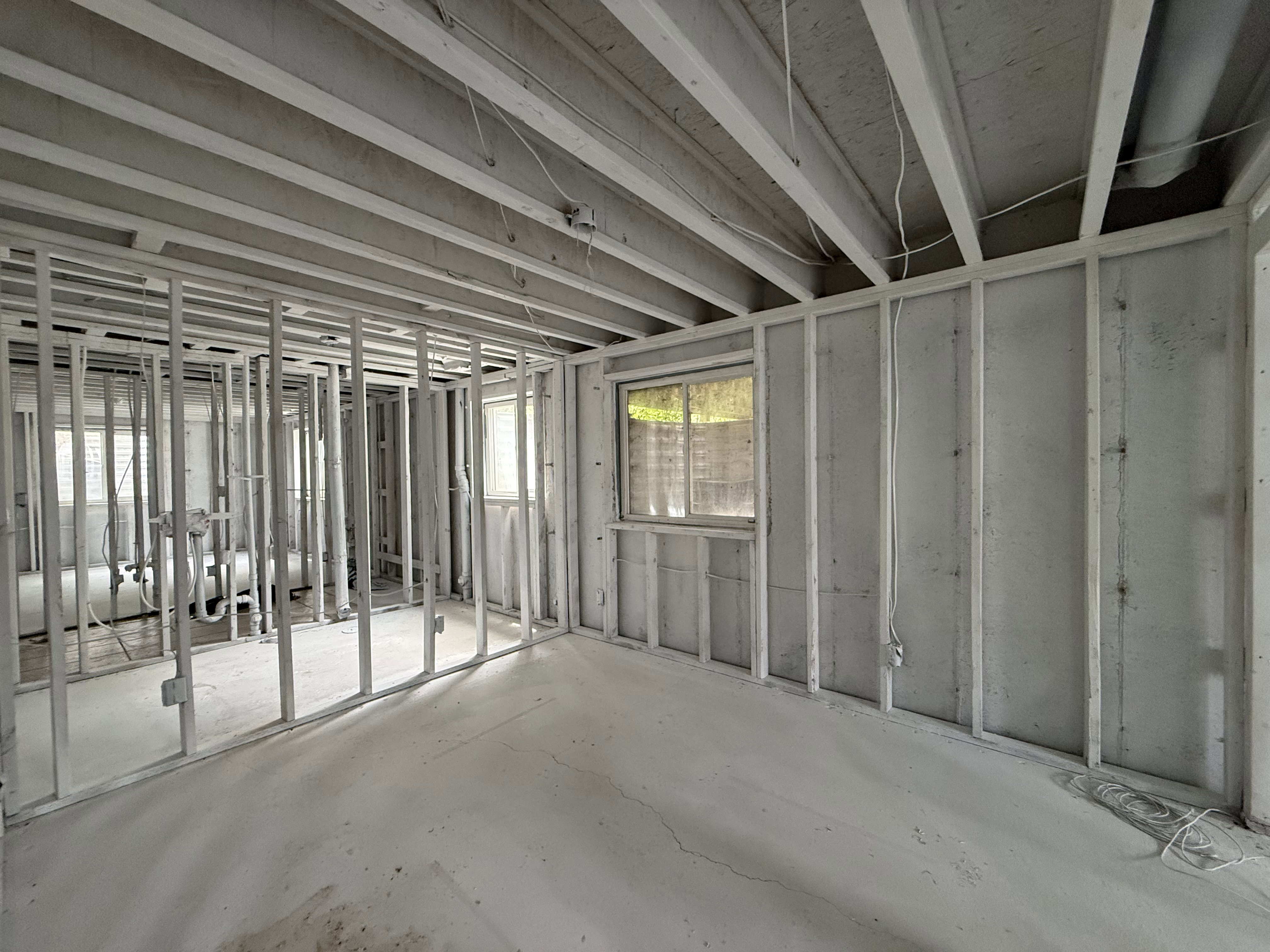 Framed basement area featuring exposed ceiling joists, concrete flooring, and multiple windows providing natural light