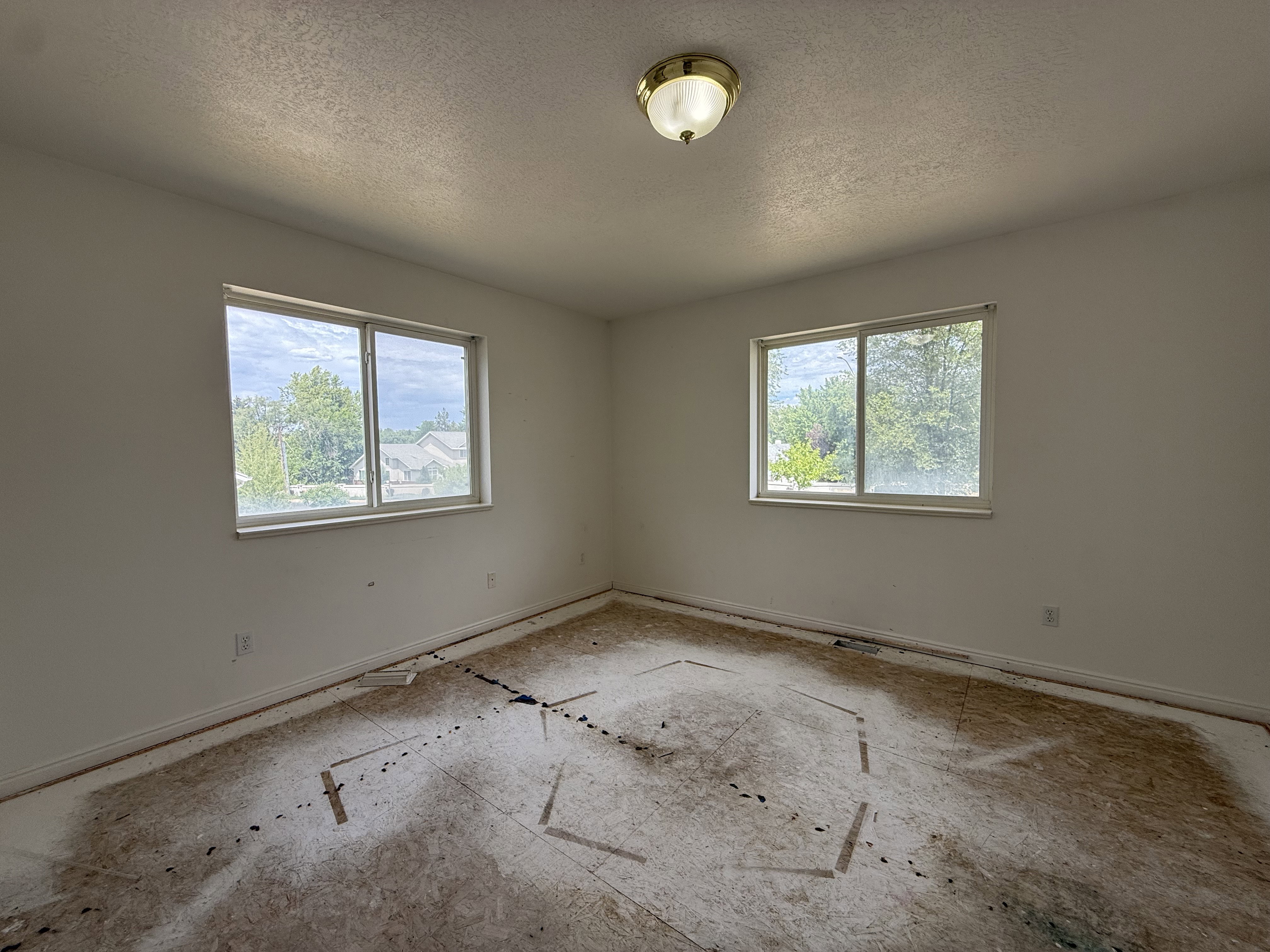 Room featuring two windows, a ceiling-mounted light fixture, and baseboard trim