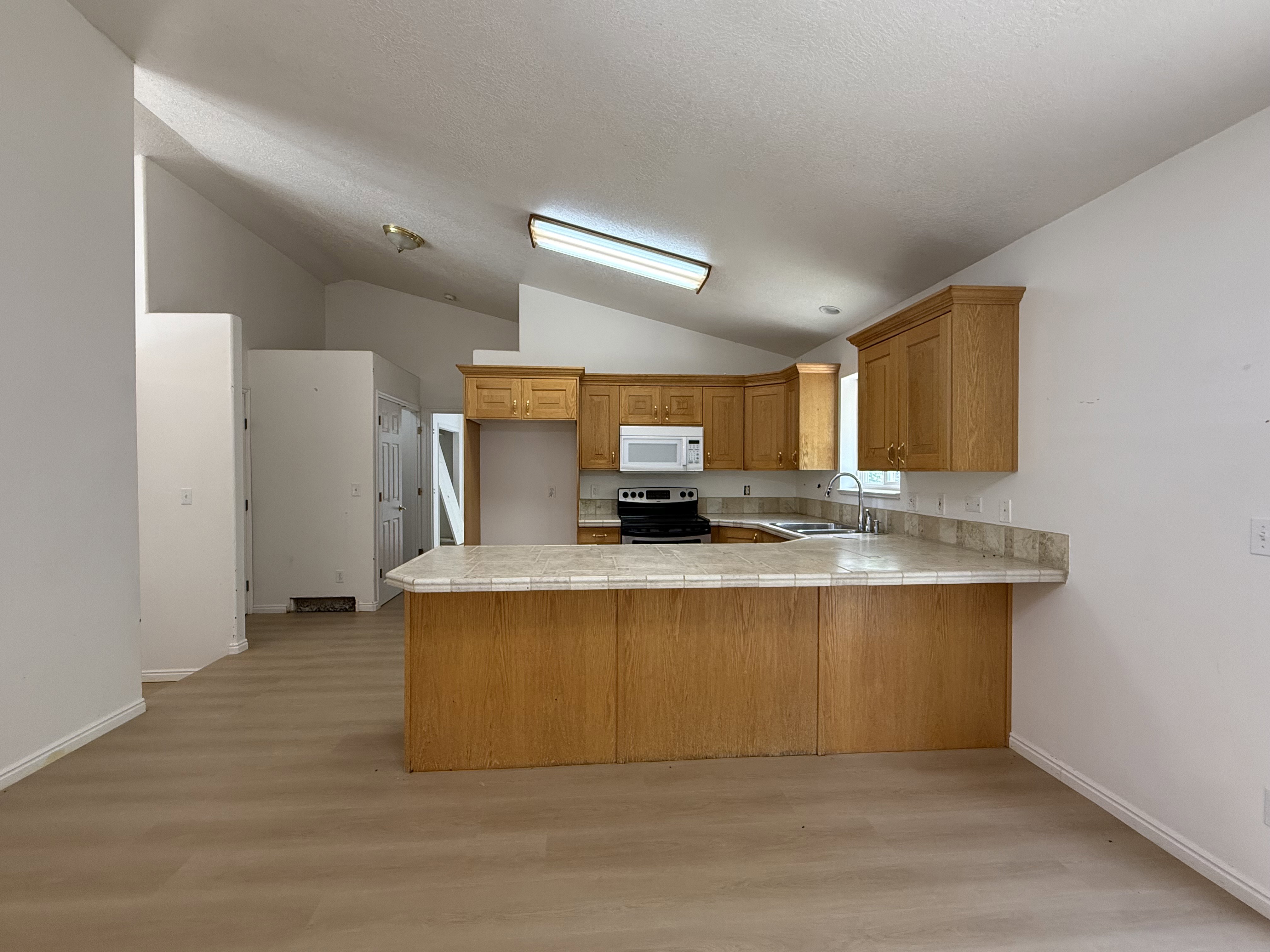 Kitchen featuring wood-finish cabinetry, light-toned countertops, and a built-in microwave