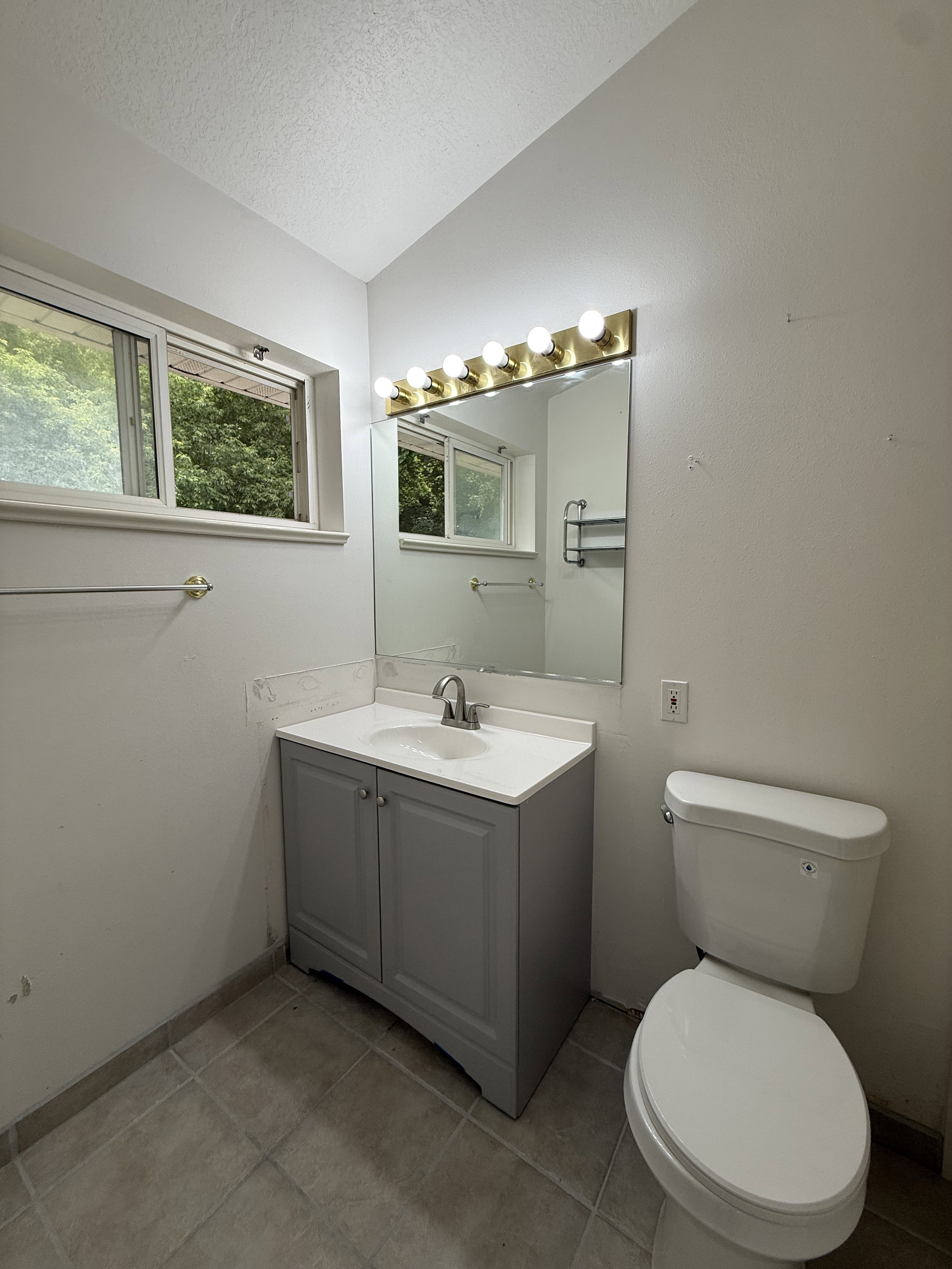 Bathroom featuring a single vanity with a white countertop and integrated sink, a gray cabinet base, and a chrome faucet