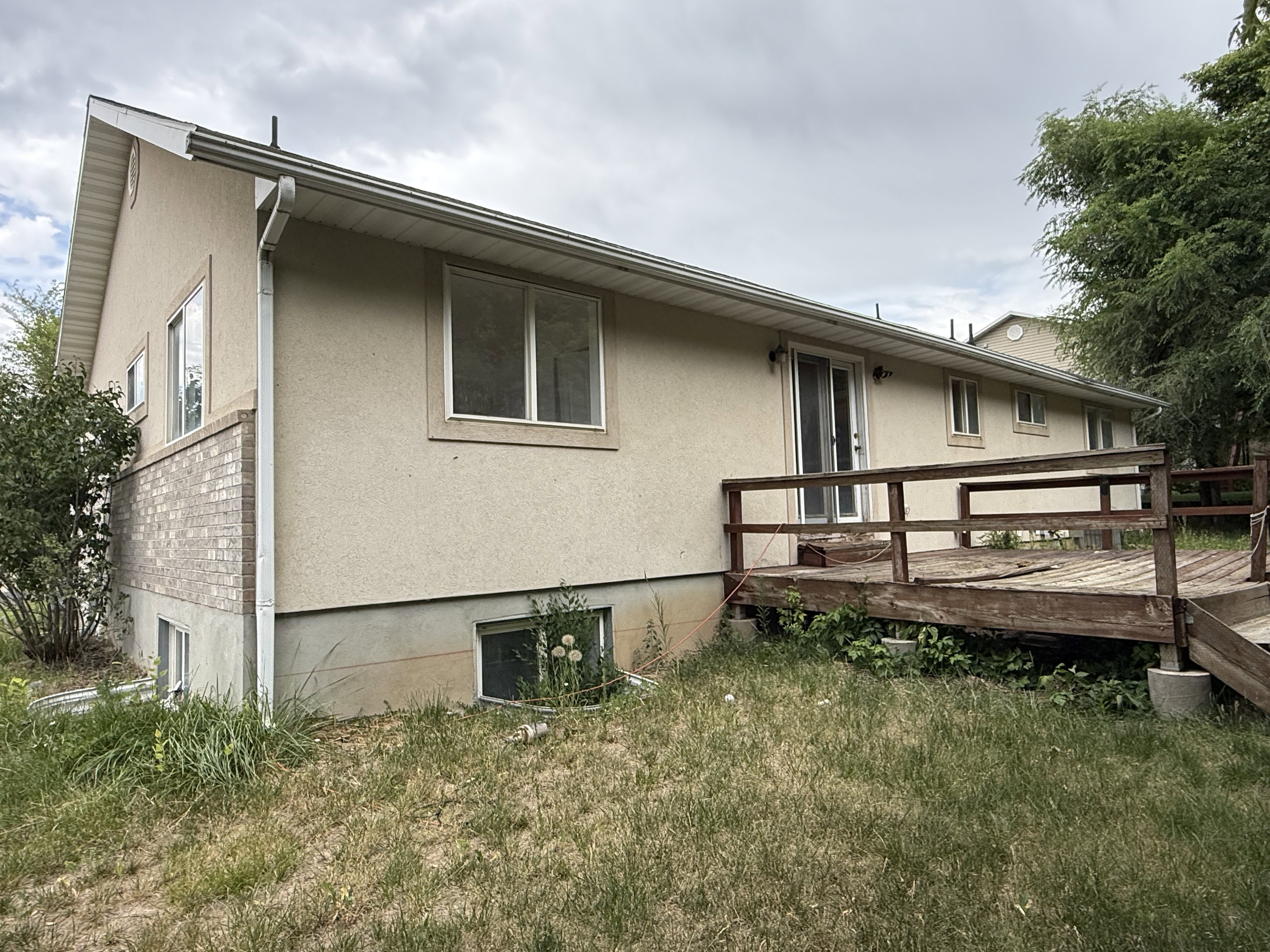 Exterior featuring a stucco finish with brick accents and a wood deck