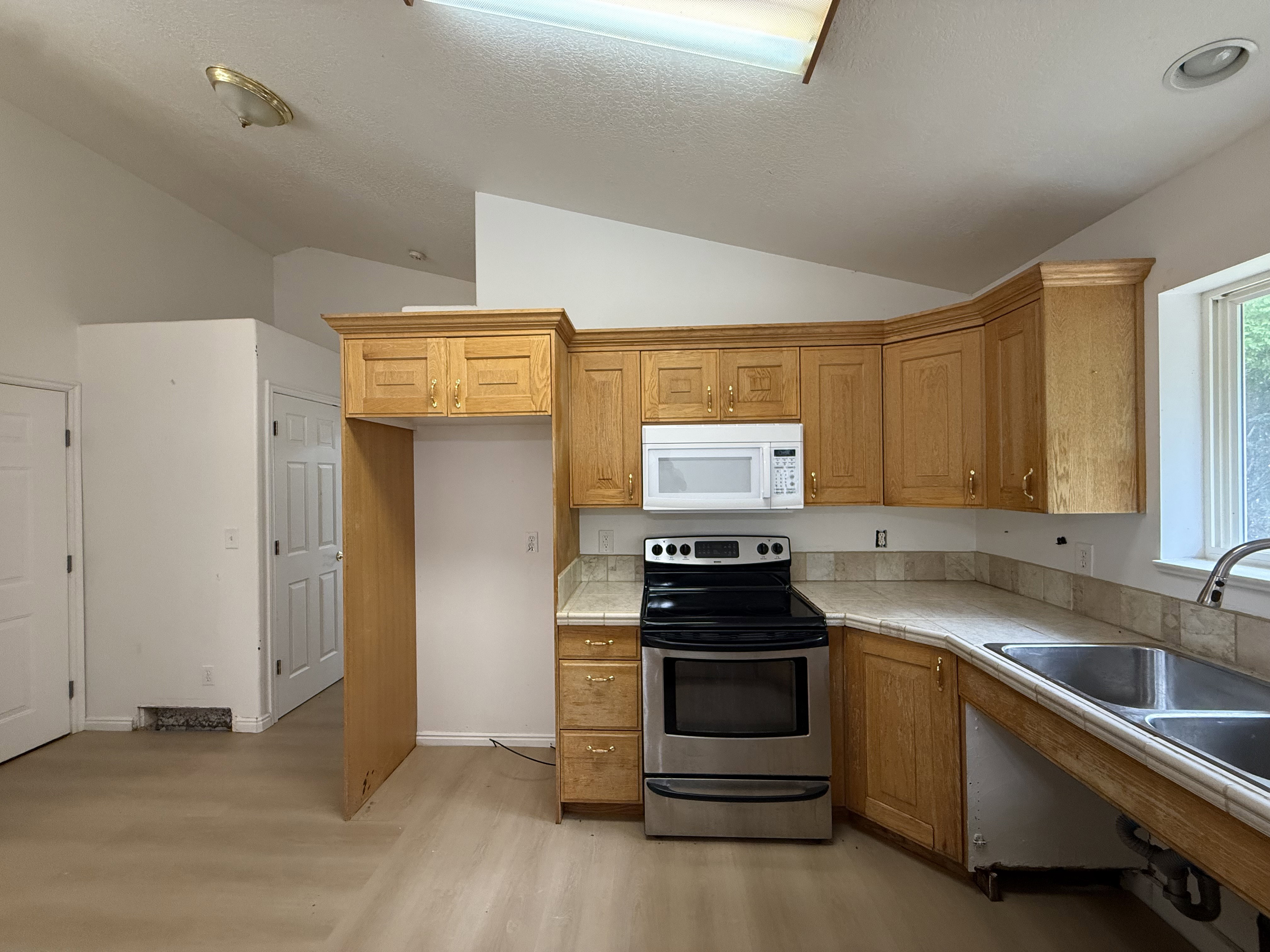 Kitchen featuring wood cabinetry, stainless steel range, built-in microwave, and a double basin sink