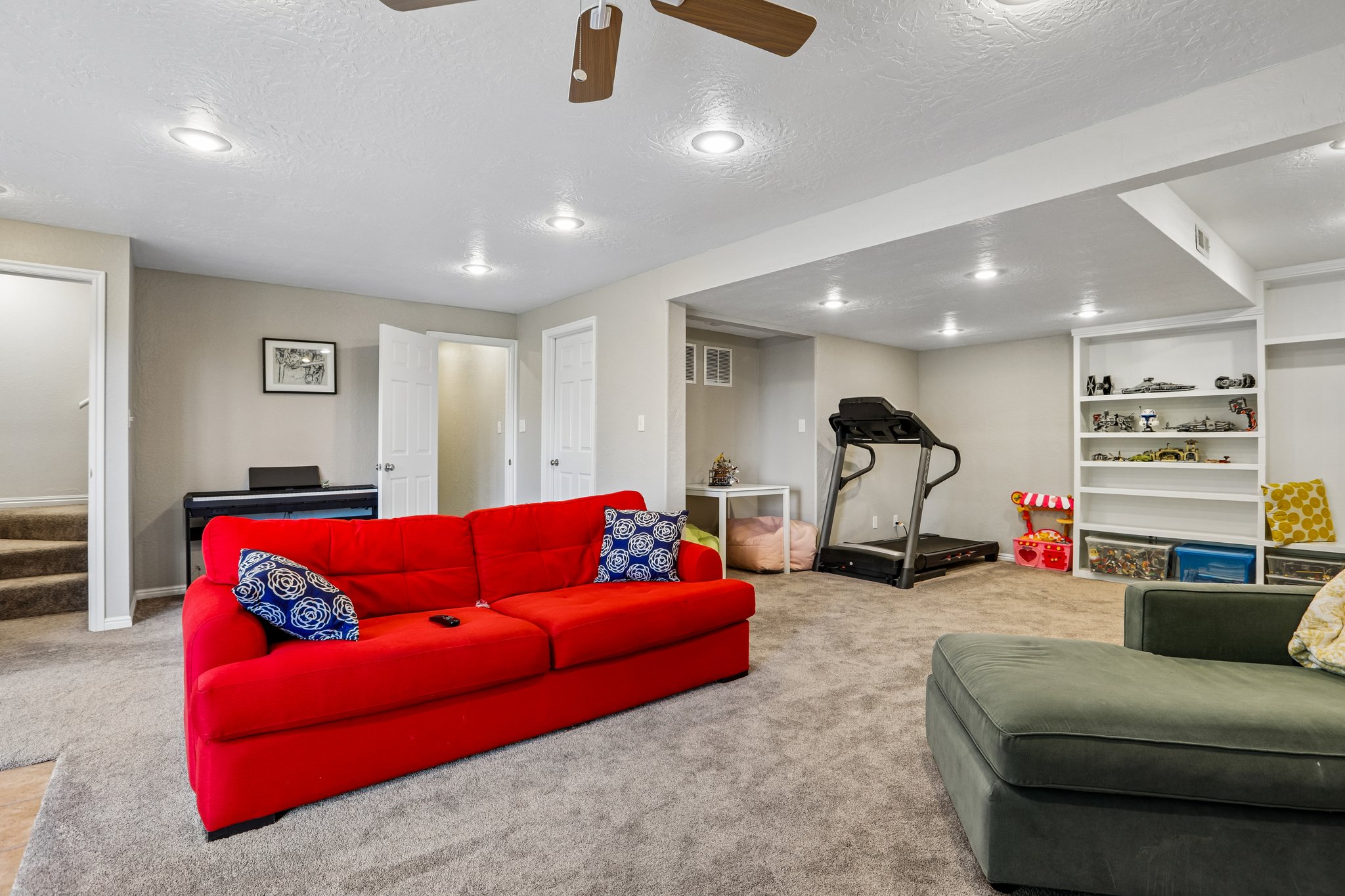 Spacious lower level featuring plush carpeting, recessed lighting, built-in shelving, and a ceiling fan