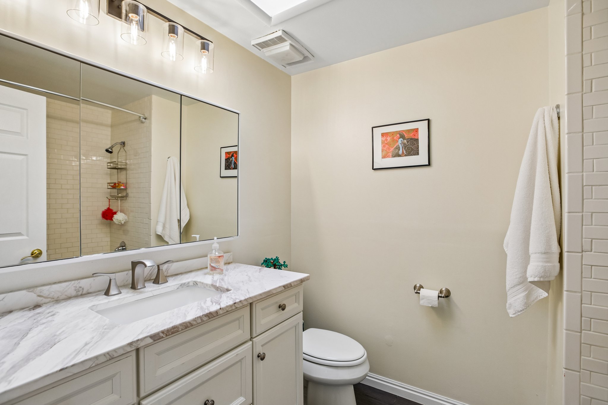 Bathroom featuring a white vanity with an integrated rectangular sink, a light-colored stone-finish countertop, and a large mirrored medicine cabinet