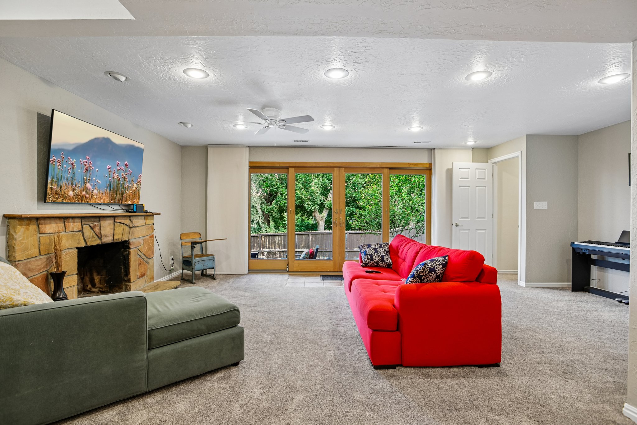 Living area featuring a stone-clad fireplace, recessed lighting, and a ceiling fan