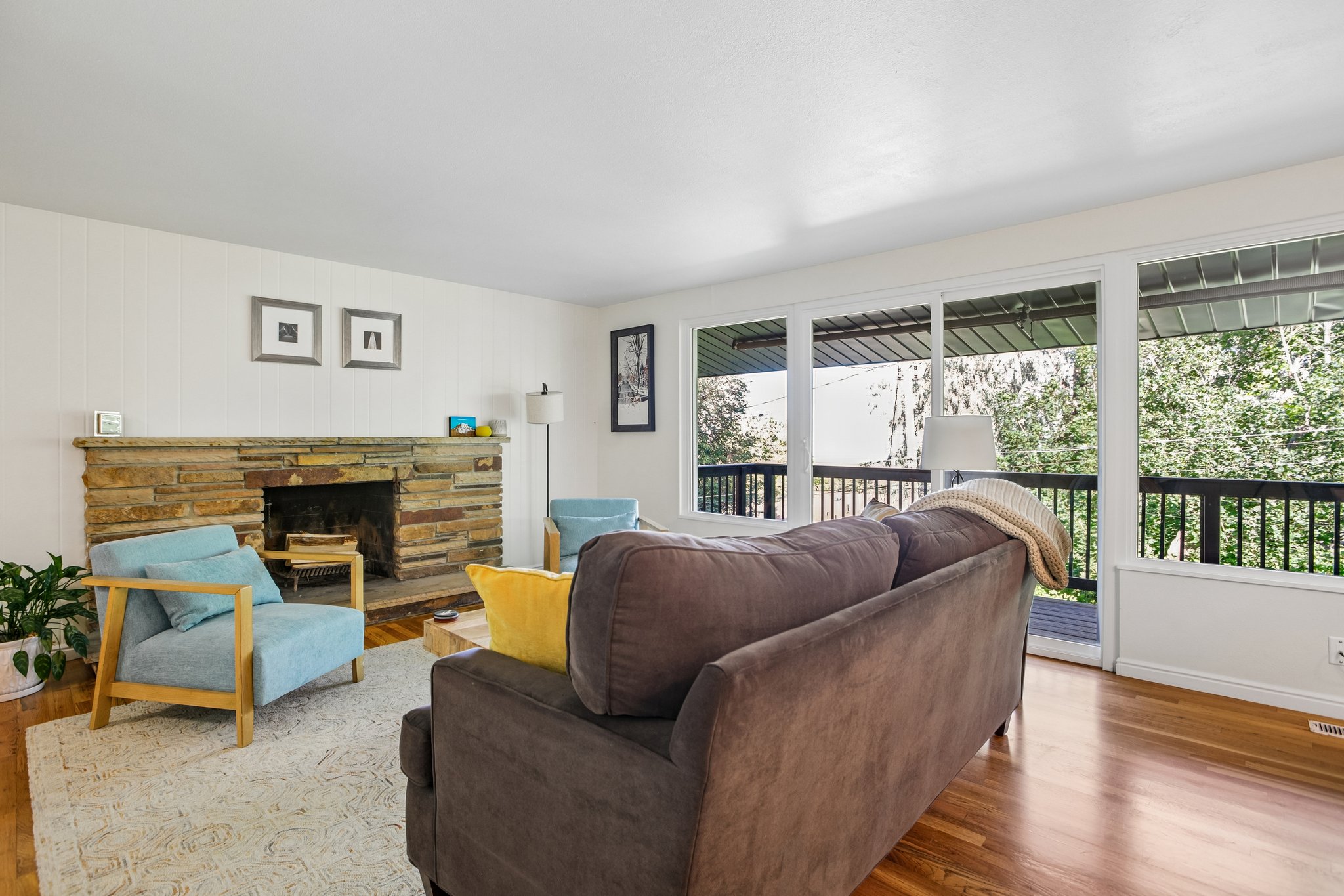 Living area featuring a stone-clad fireplace, light wood-finish flooring, and white paneled walls