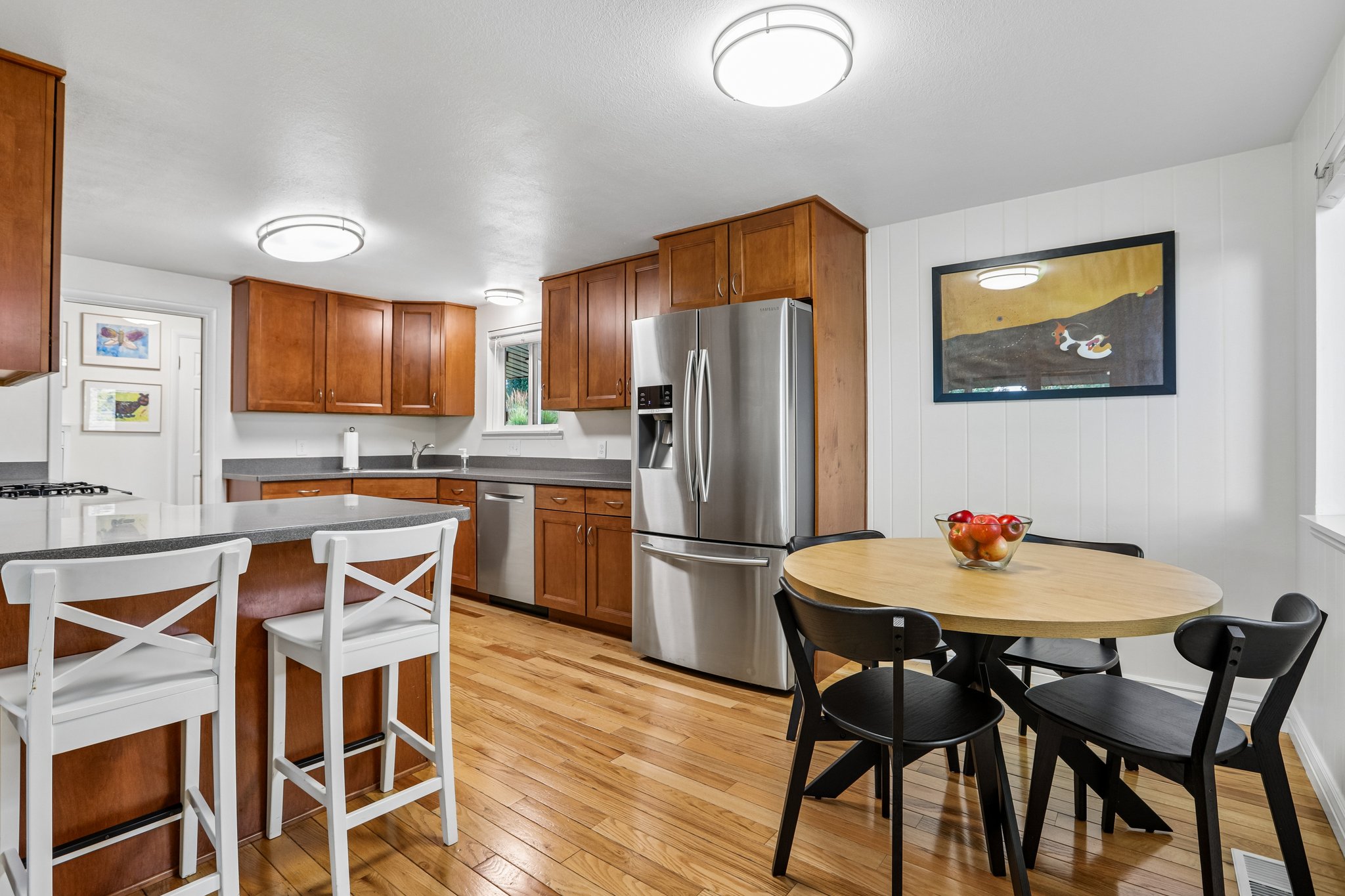 Kitchen featuring wood-finish flooring, wood cabinetry, stainless steel appliances, and a central island with countertop seating