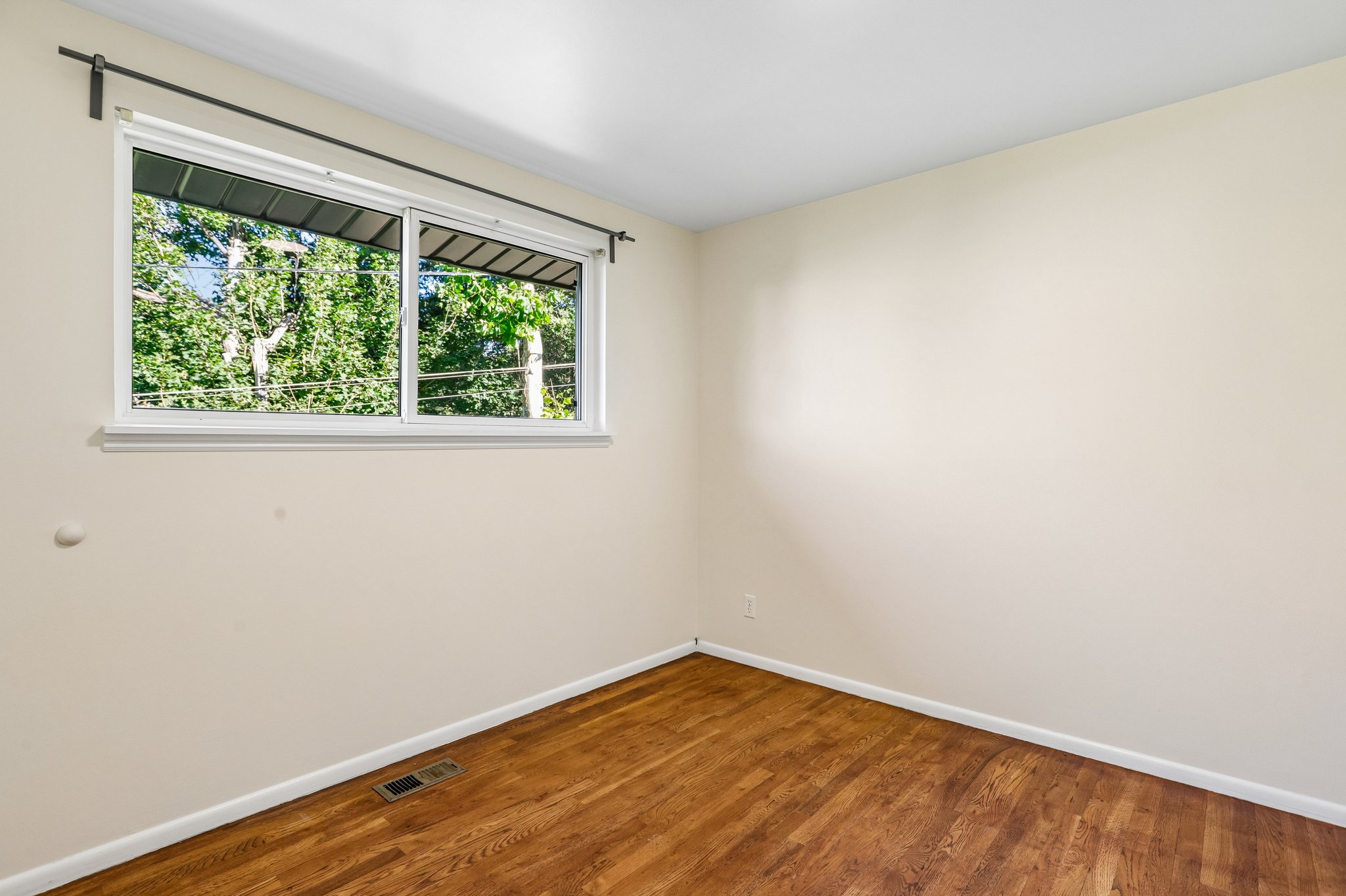 Bright interior space featuring a double-pane window, wood-finish flooring, and a neutral wall palette