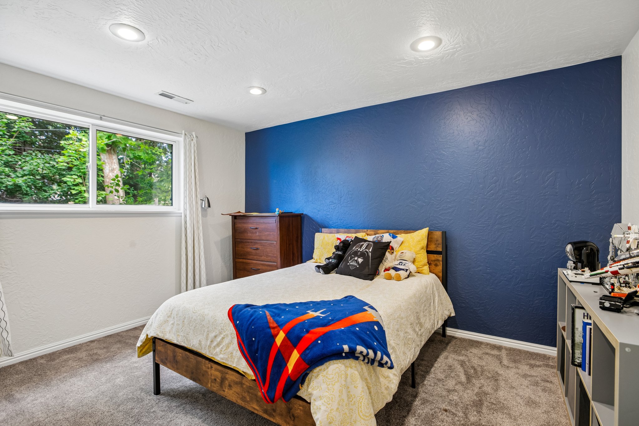 Carpeted room featuring a large window, recessed lighting, and a textured accent wall