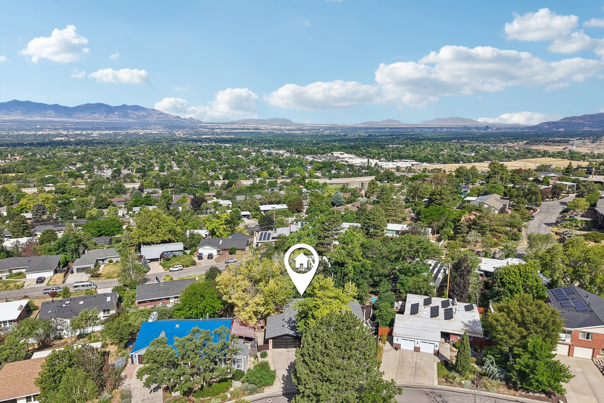 Expansive aerial perspective showcasing a residential area with mature tree coverage and distant mountains