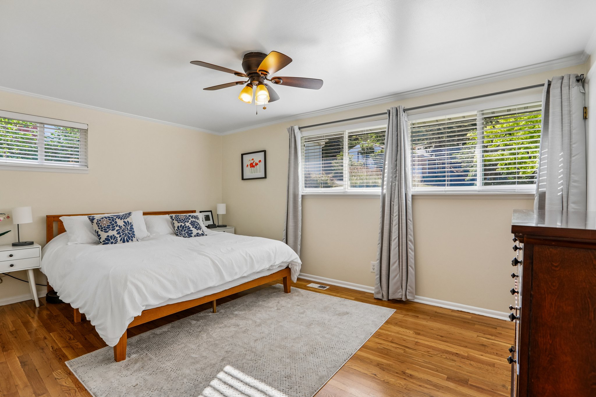 Spacious room featuring wood-finish flooring, light-toned walls, and a ceiling fan with integrated lighting