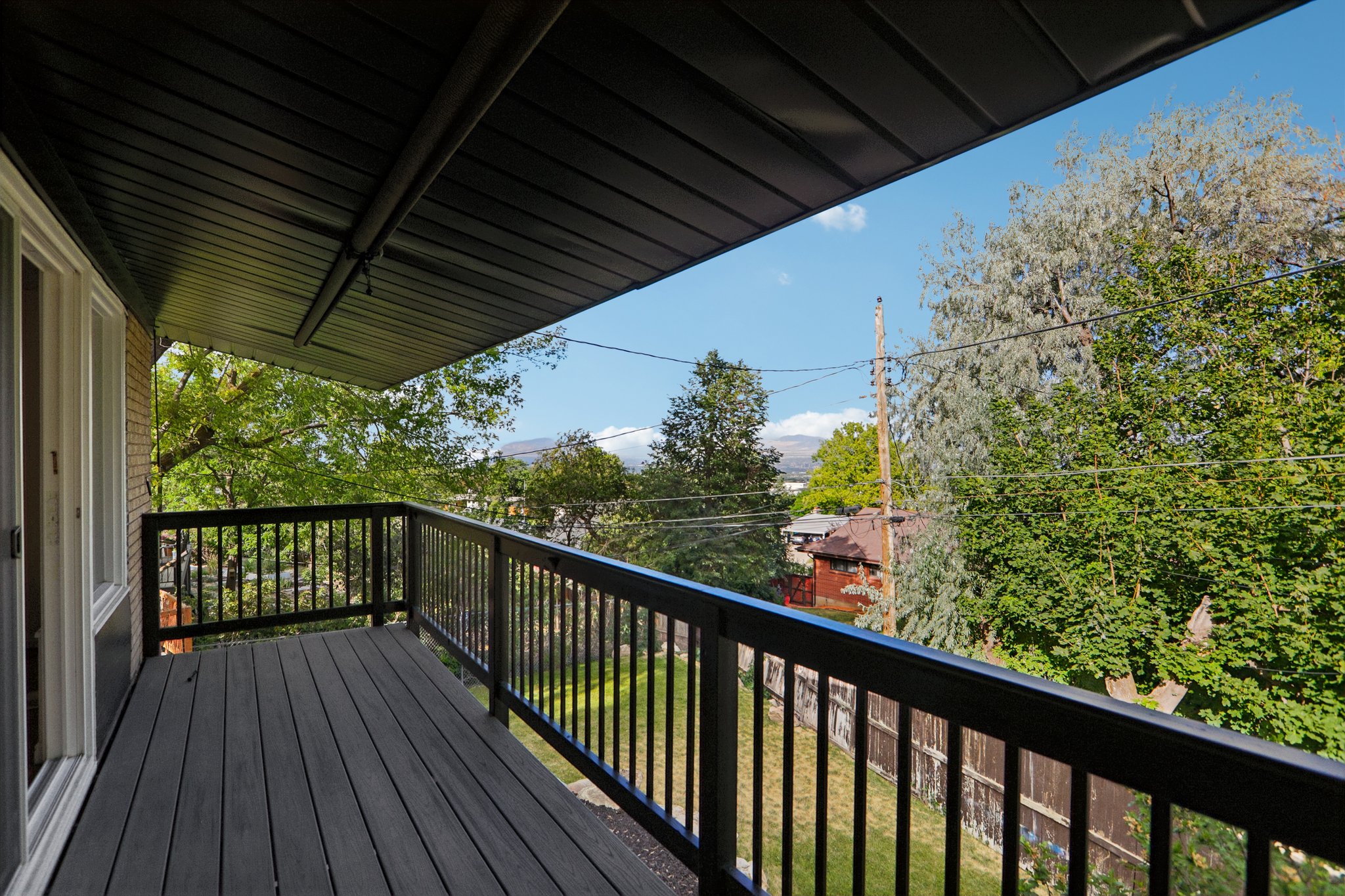 Spacious outdoor deck featuring dark composite decking, black metal railings, and a dark soffit overhead