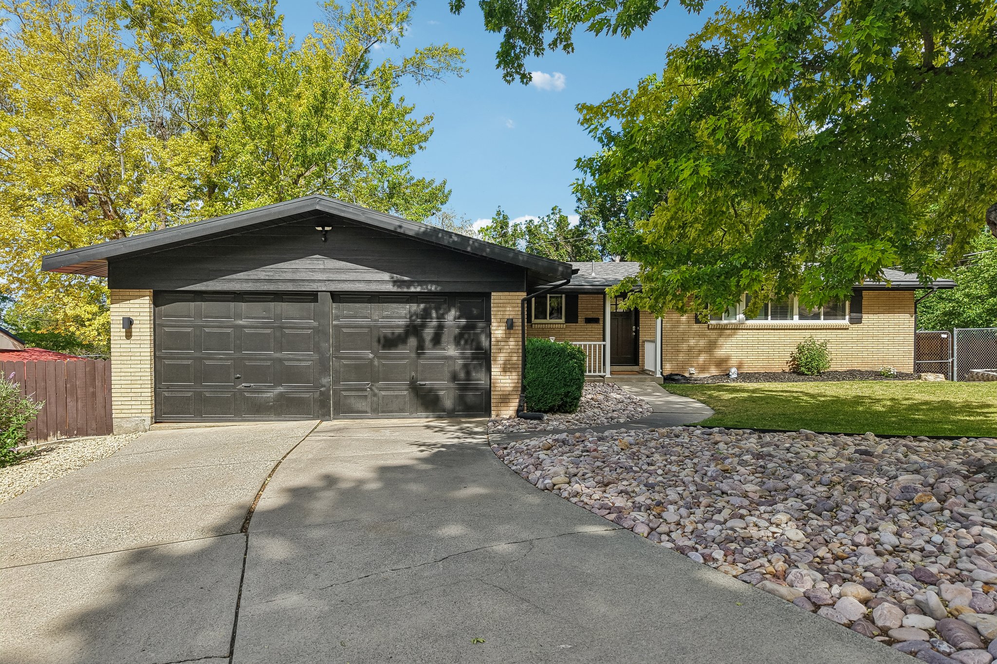 Brick facade residence featuring a two-car garage with dark paneled doors