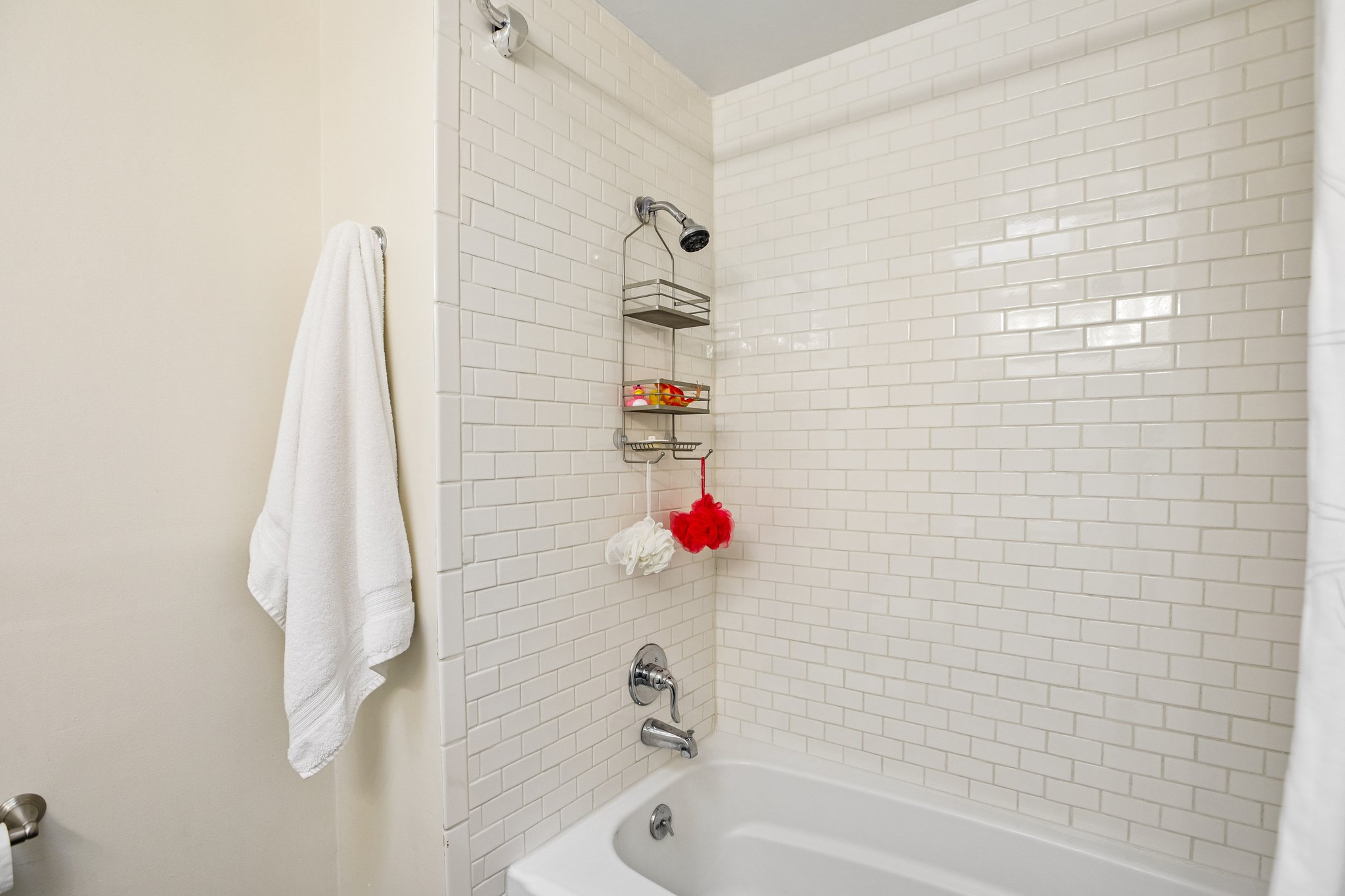 Bathtub with subway tile surround, chrome fixtures, and a showerhead