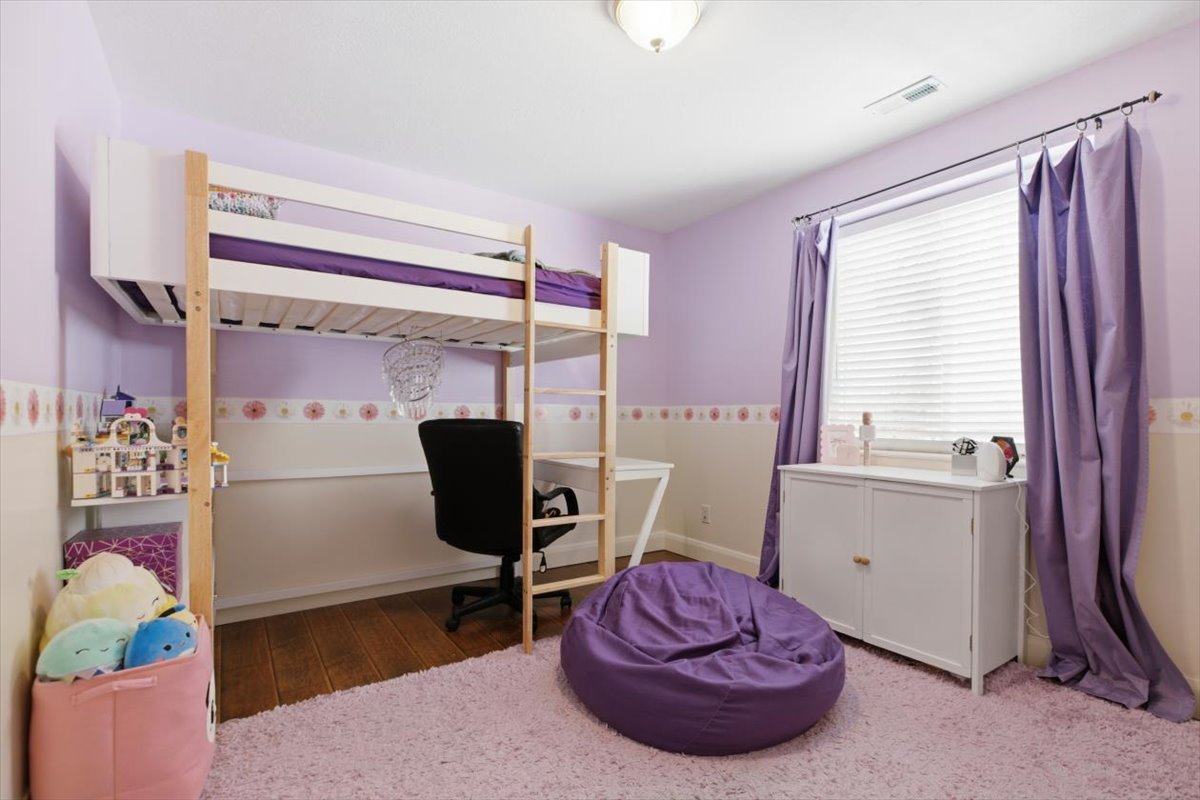 Room featuring wood-finish flooring, a window with blinds and curtains, and a ceiling-mounted light fixture