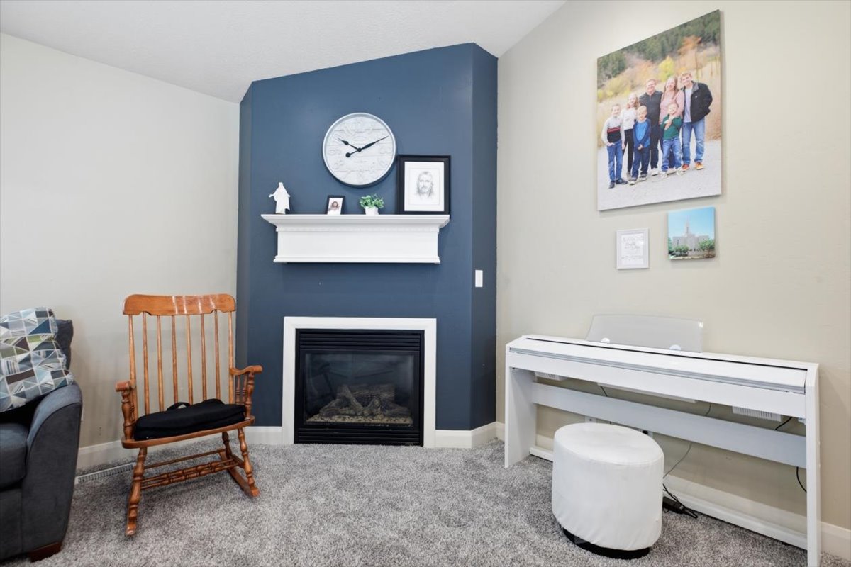 Corner fireplace featuring a white mantel, contrasting blue accent wall, and a hearth with a dark surround