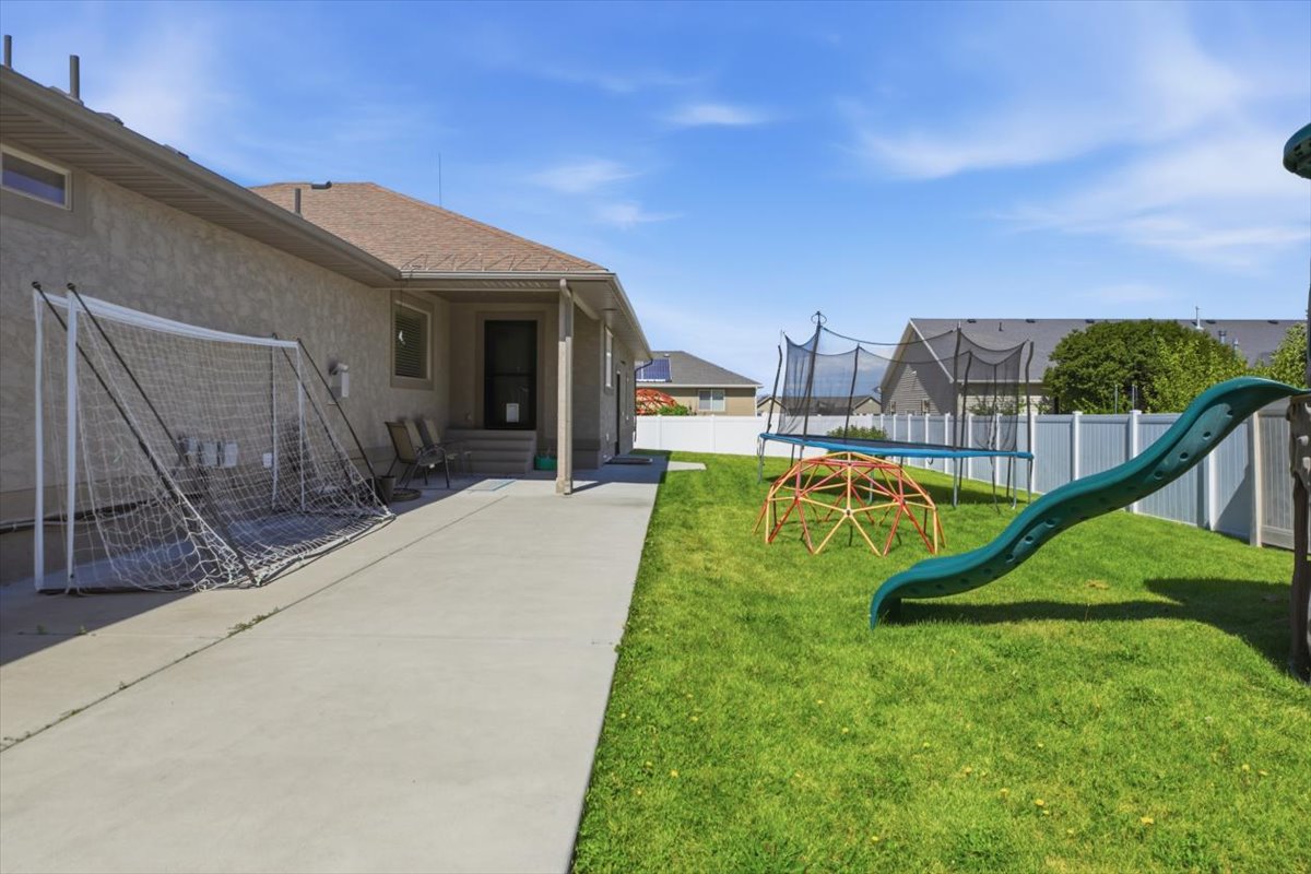 Expansive backyard featuring a lush lawn and a concrete patio