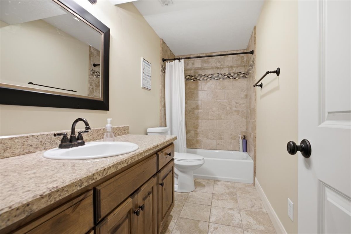 Bathroom featuring a dark wood vanity with a light-toned countertop, an oval undermount sink, and a dark bronze faucet