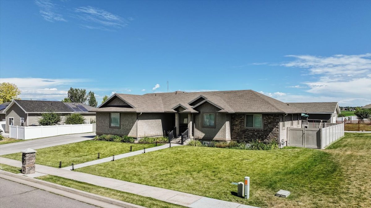 Ranch-style residence featuring a stone and stucco exterior, an asphalt shingle roof, and an attached two-car garage