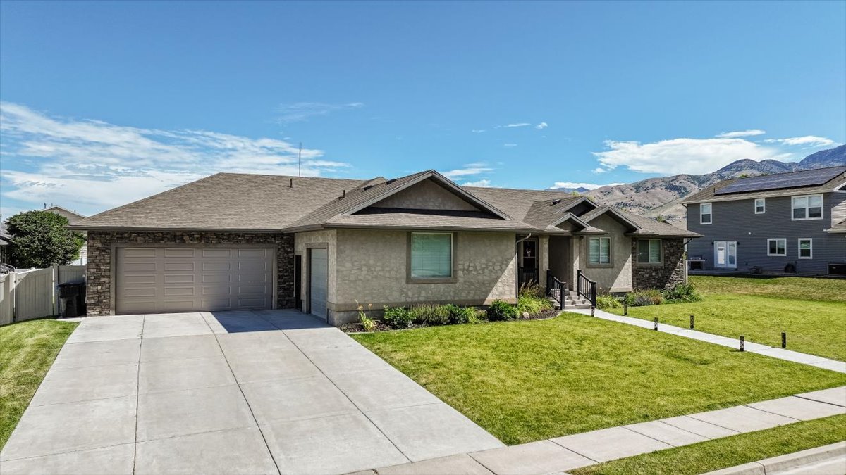 Ranch-style residence featuring a prominent two-car garage, stone and stucco exterior, and a concrete driveway