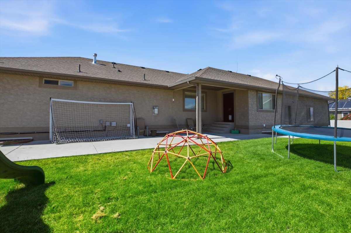 Manicured lawn with a concrete patio extending along the rear of the residence