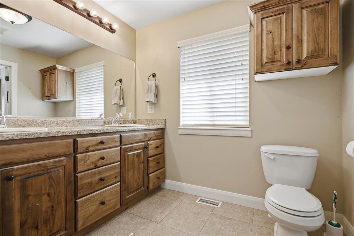 Spacious bathroom featuring a double vanity with wood cabinetry, light-toned countertop, and a large wall-mounted mirror
