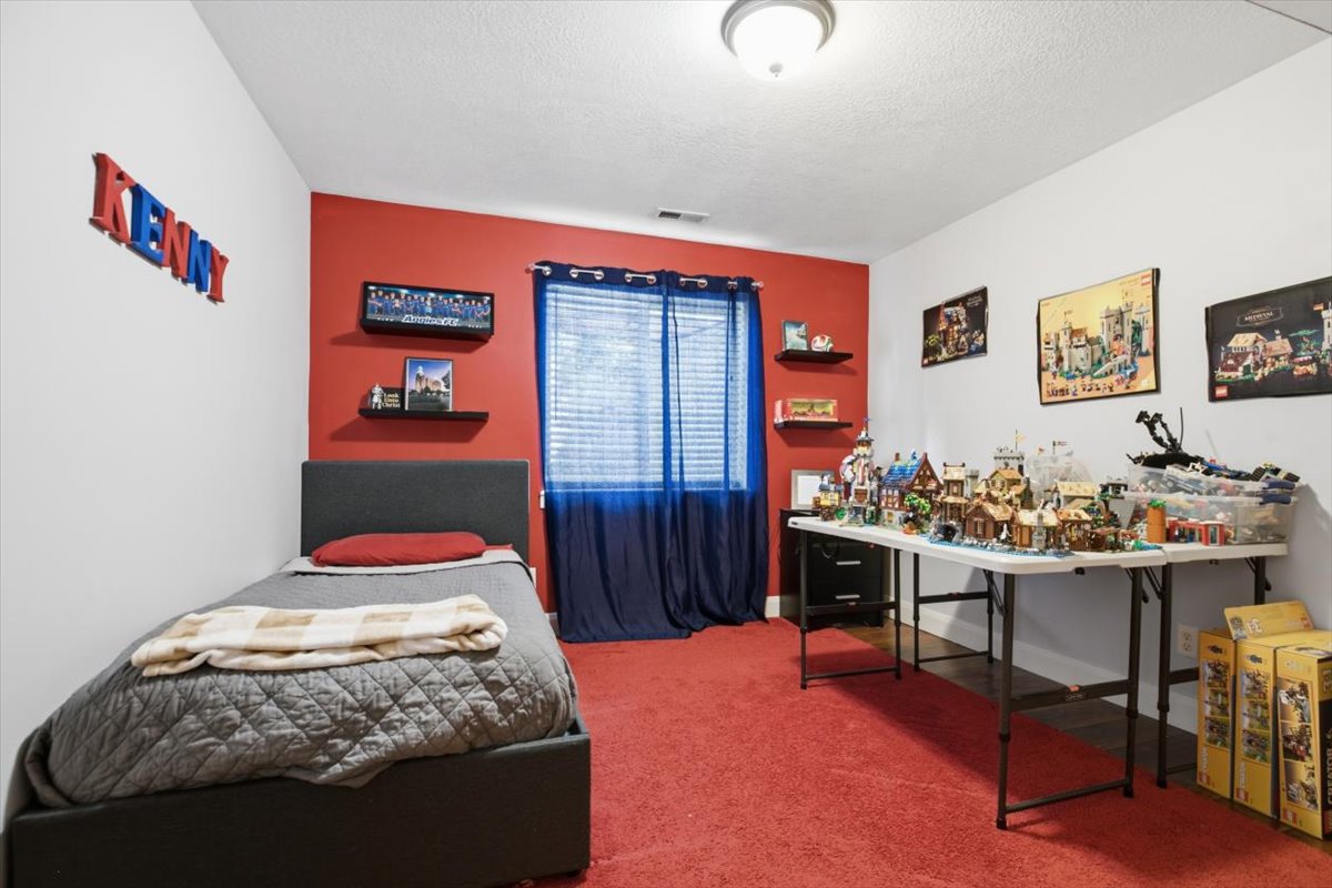 Room featuring a red accent wall, white painted walls, and red carpet flooring
