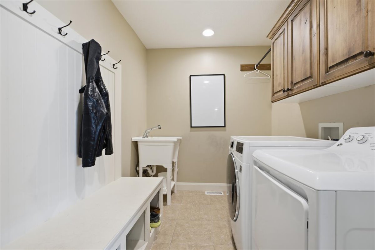 Utility room with tile flooring, built-in mudroom bench with coat hooks, and a utility sink